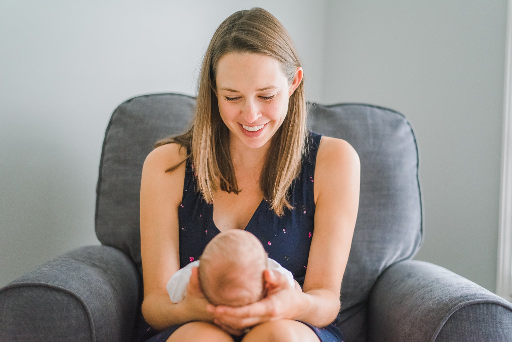 mother in rocker looking at newborn baby boy