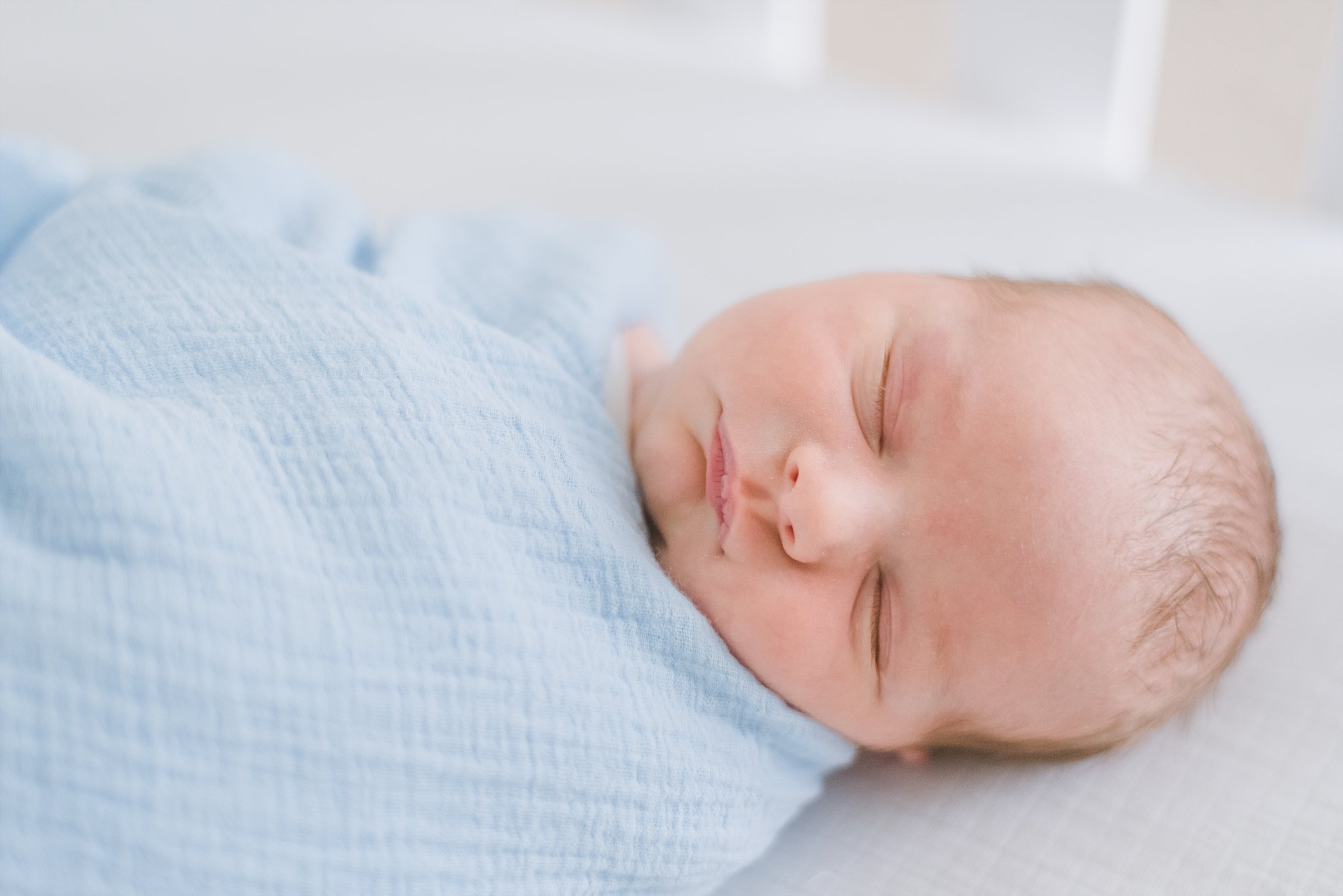 swaddled and sleepy newborn baby boy