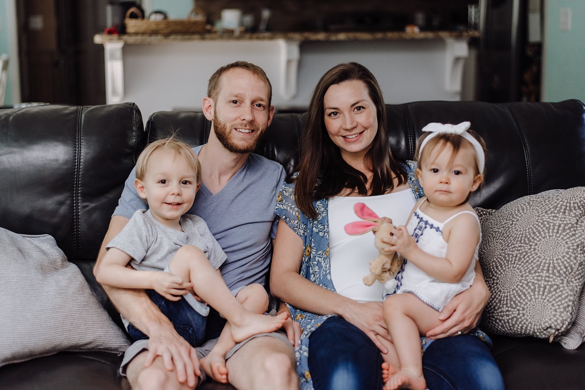 family of 4 on couch in home maternity session