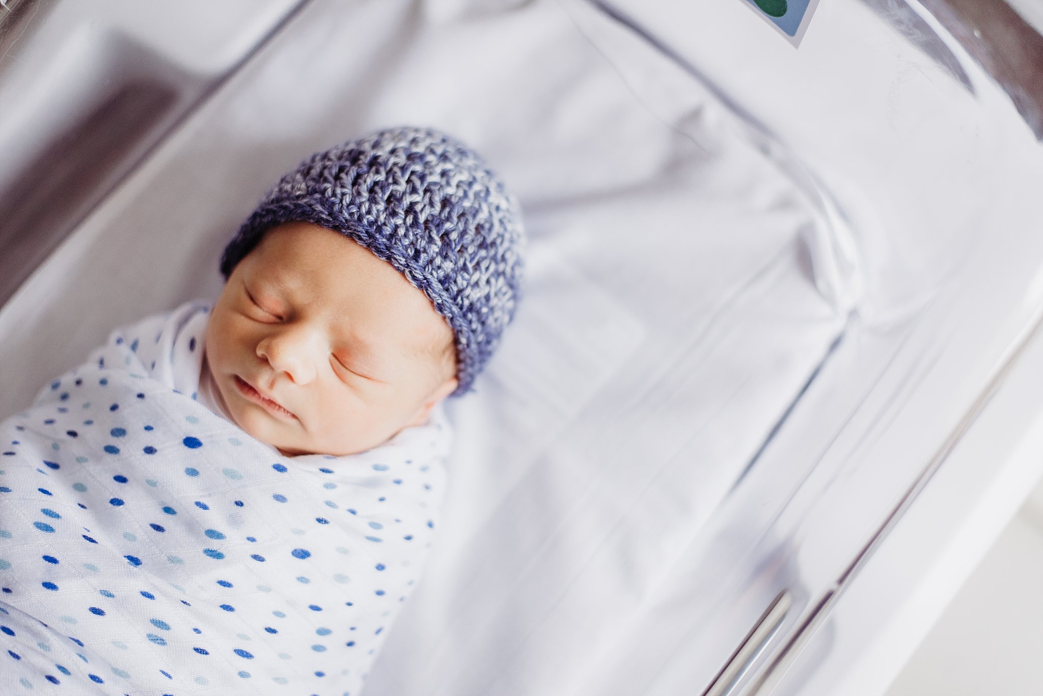 newborn baby boy with blue hat on in hospital bassinet Piedmont Atlanta hospital