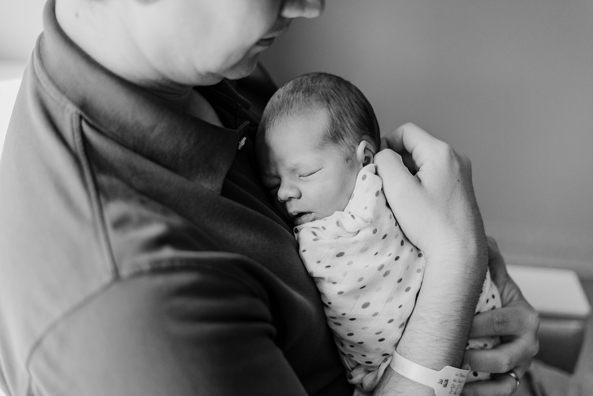 newborn baby boy snuggled in to father's chest