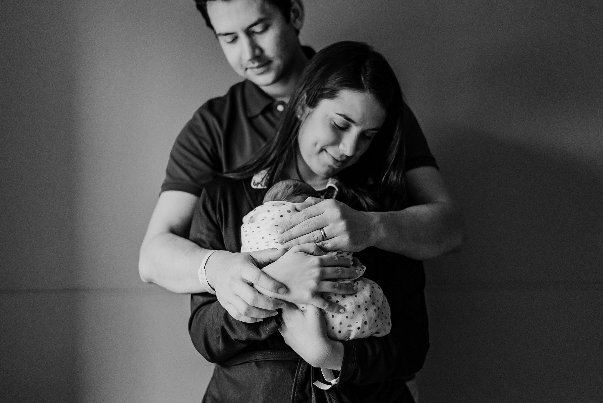 mother and father snuggling newborn baby boy