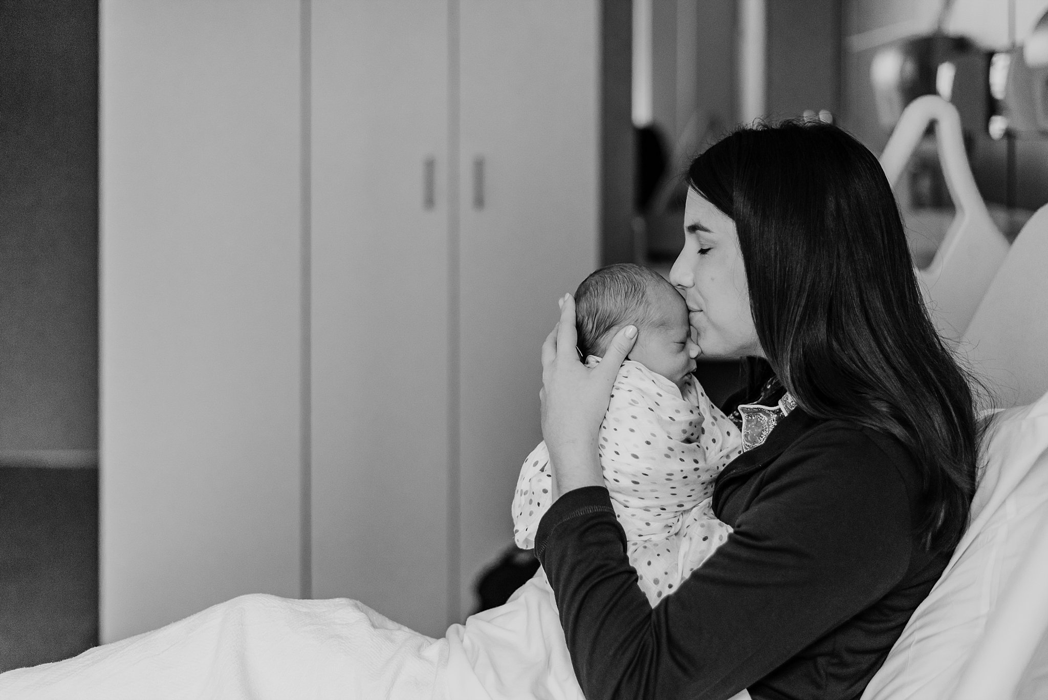 mother kissing newborn baby boy