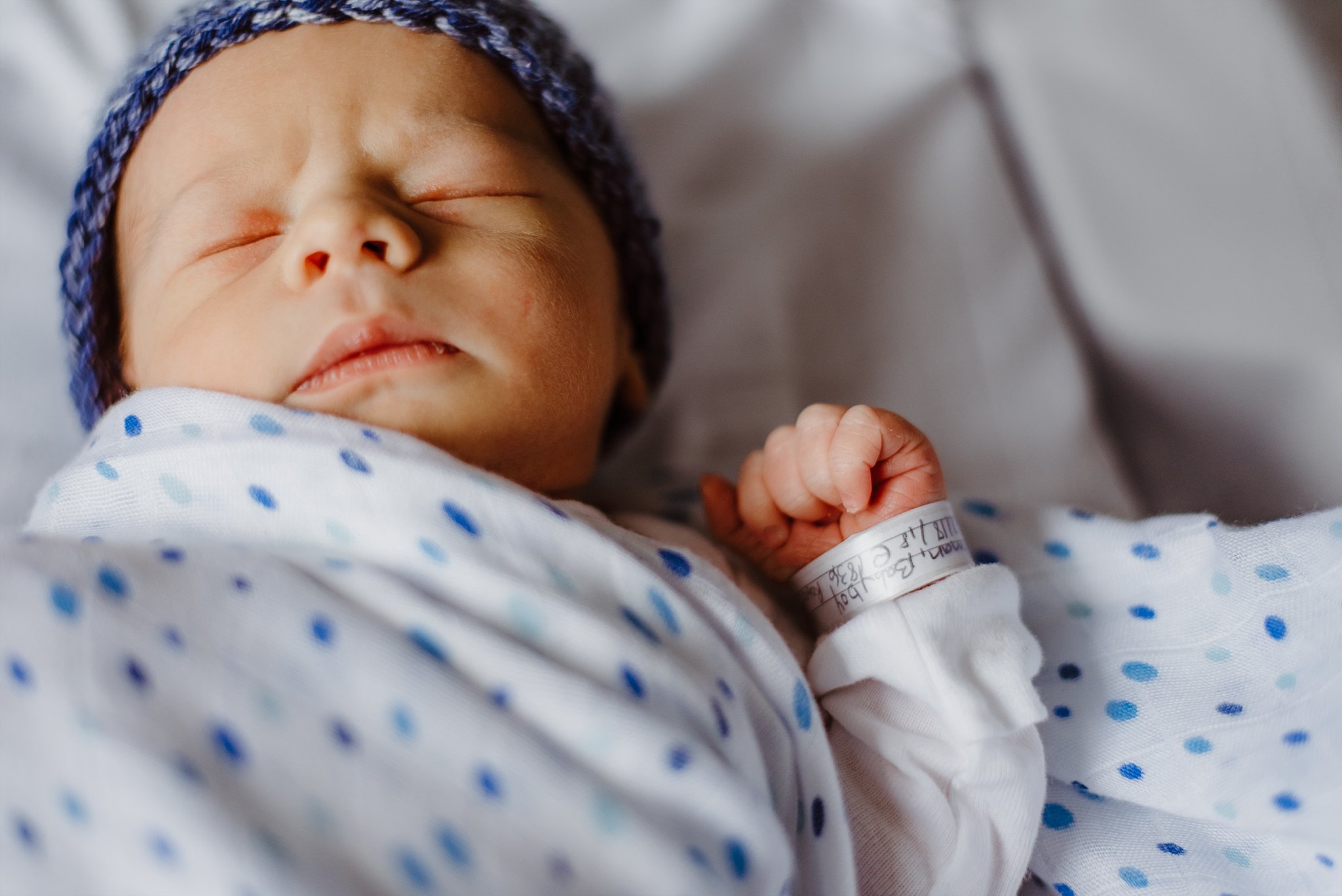 Newborn baby boy in hospital bassinet with hospital bracelet on