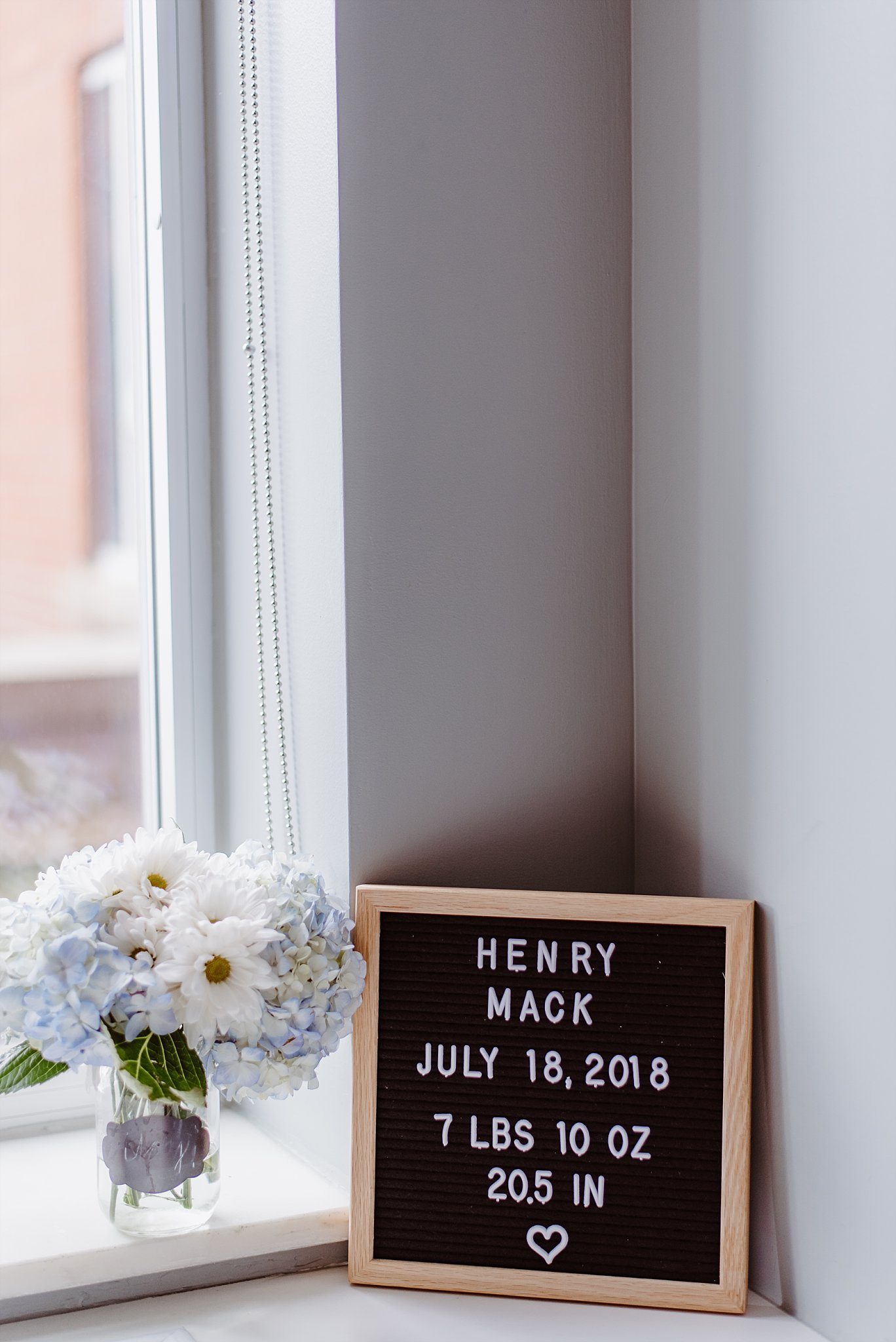 letterboard next to flowers with baby's name birth date and weight