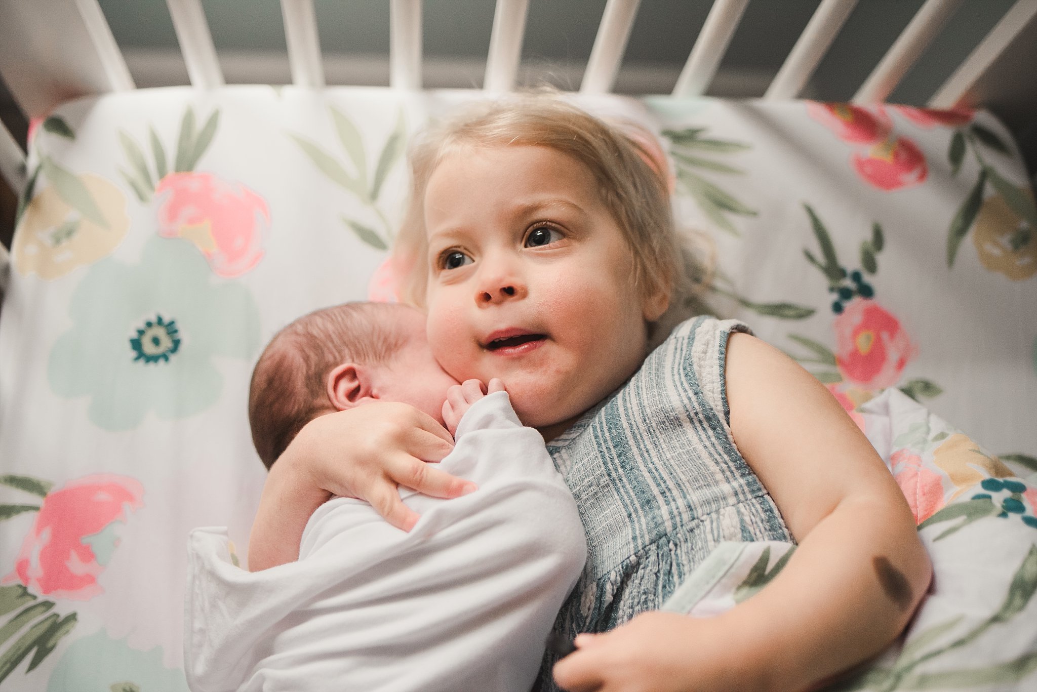 toddler hugging newborn sister