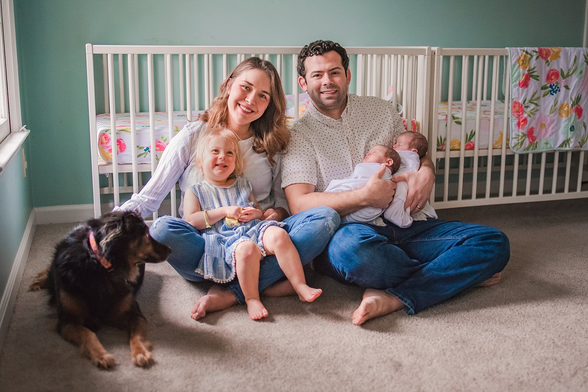 mom, dad, toddler girl, newborn twins, dog sitting in front of crib in nursery
