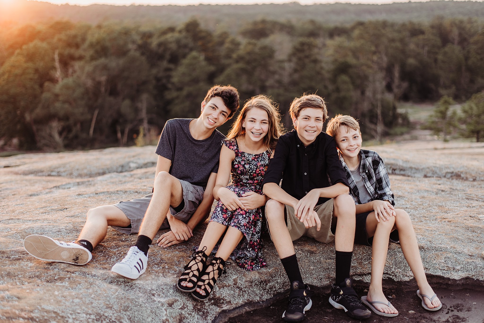 4 kids smiling and sitting at sunset on Arabia Mountain Atlanta