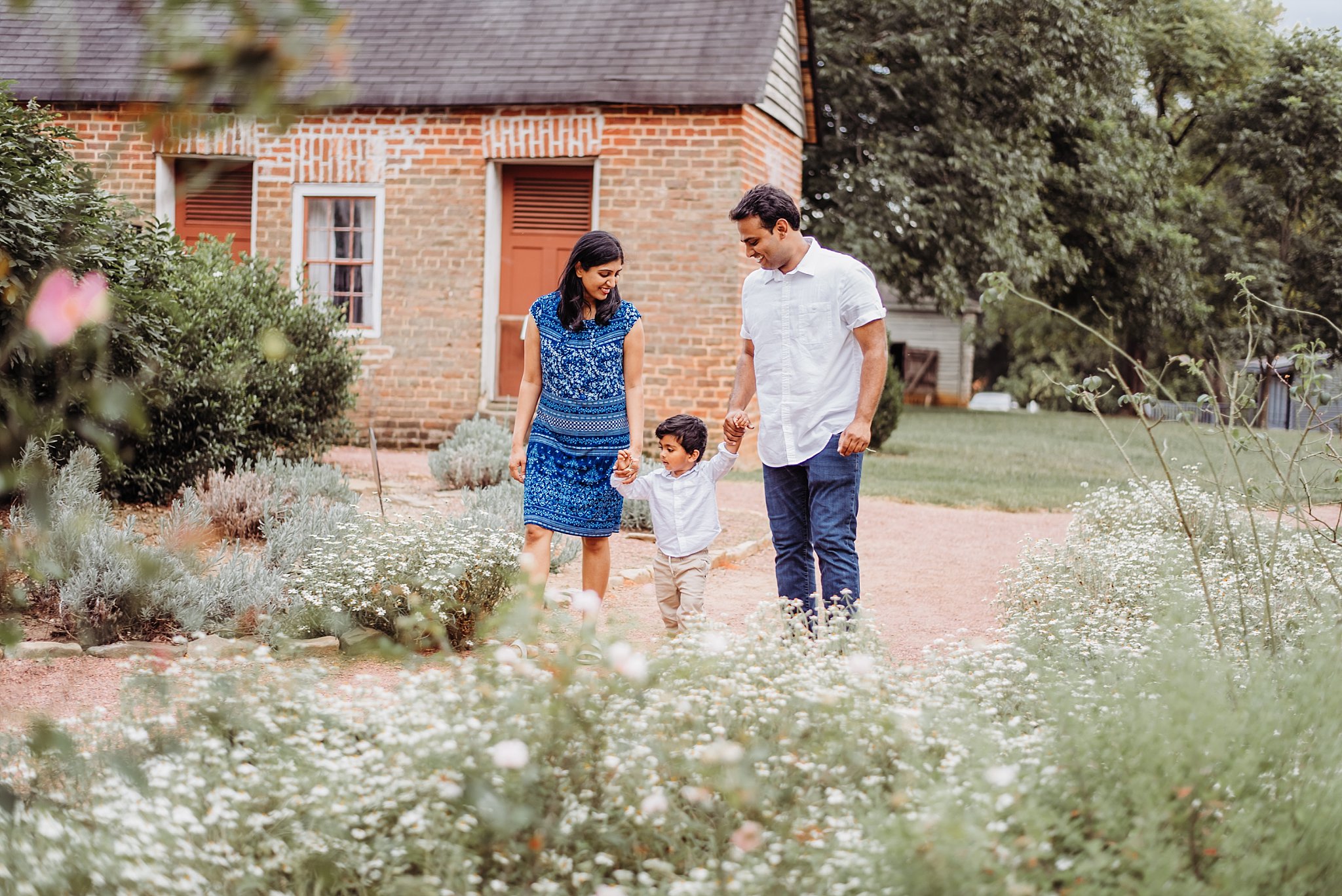 Family of 3 walking down path in gardens at Barrington Hall