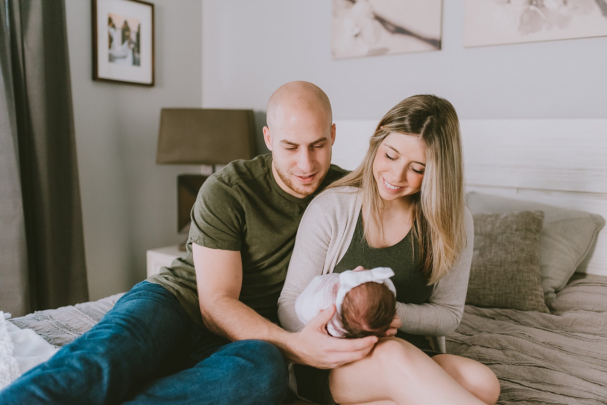 parents looking down at newborn baby girl in hands