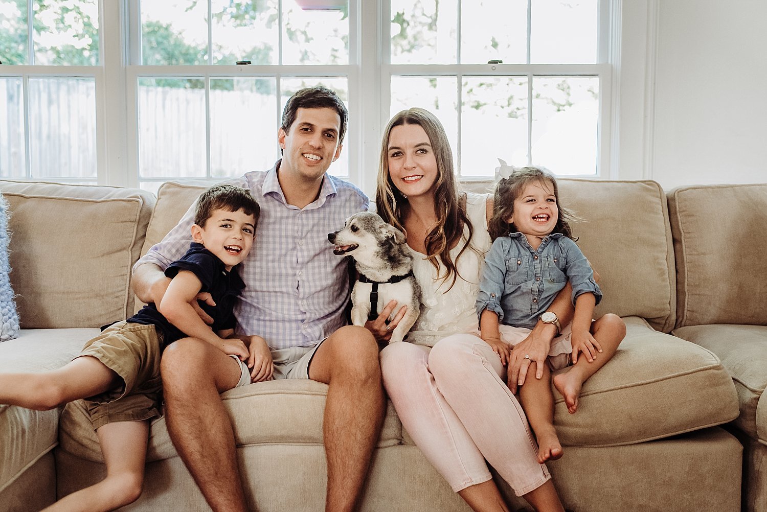 Family of four with dog sitting on couch 