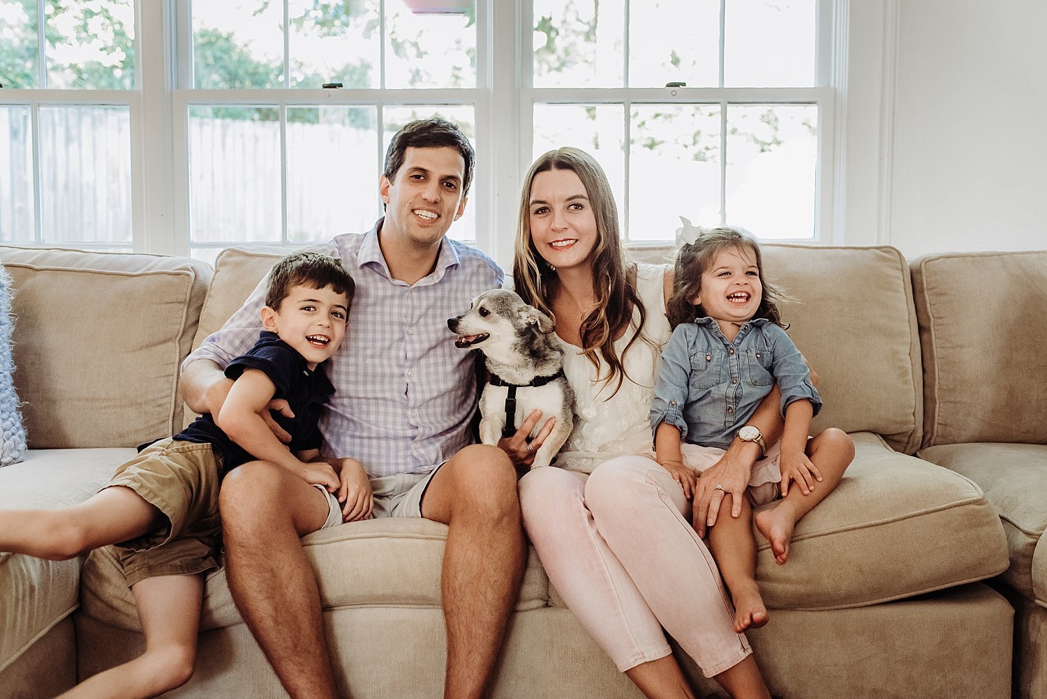 Family of four with dog sitting on couch