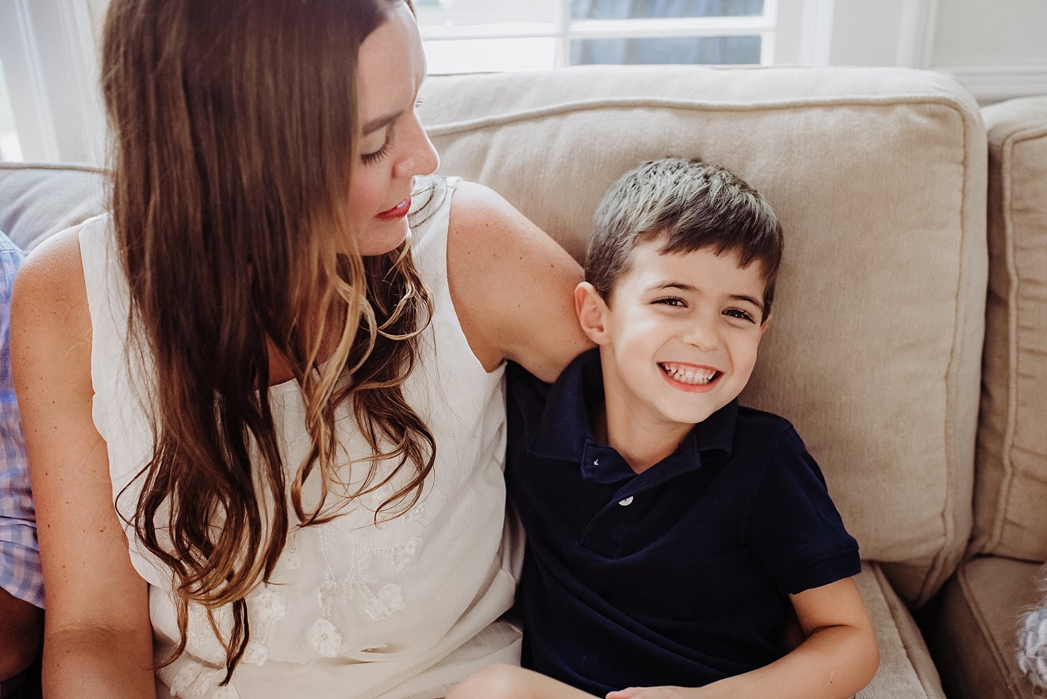 4 year old boy smiling on couch with mom 