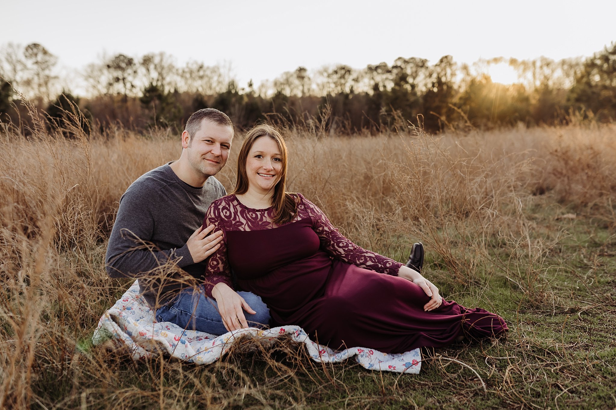 couple sitting in field at Garrard Landing Park Roswell GA maternity photo session