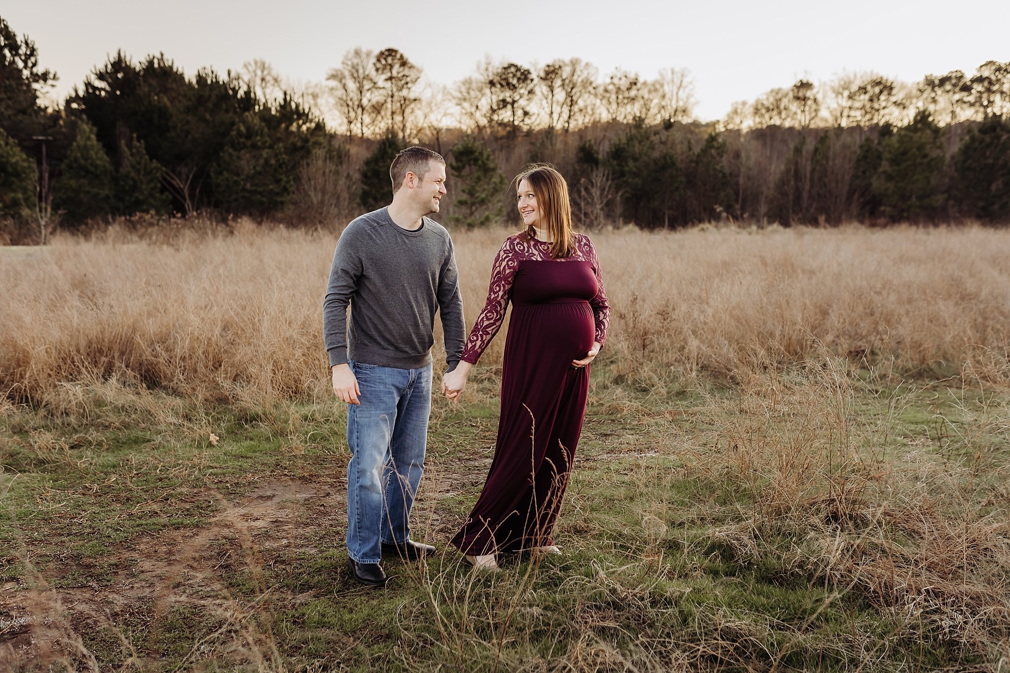 couple walking through field at Garrard Landing Park Roswell GA maternity photo session