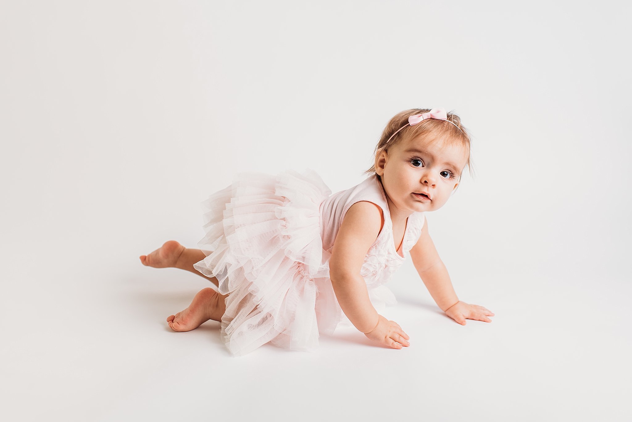 Baby crawling on white backdrop in pink dress  | Atlanta Baby Photographer