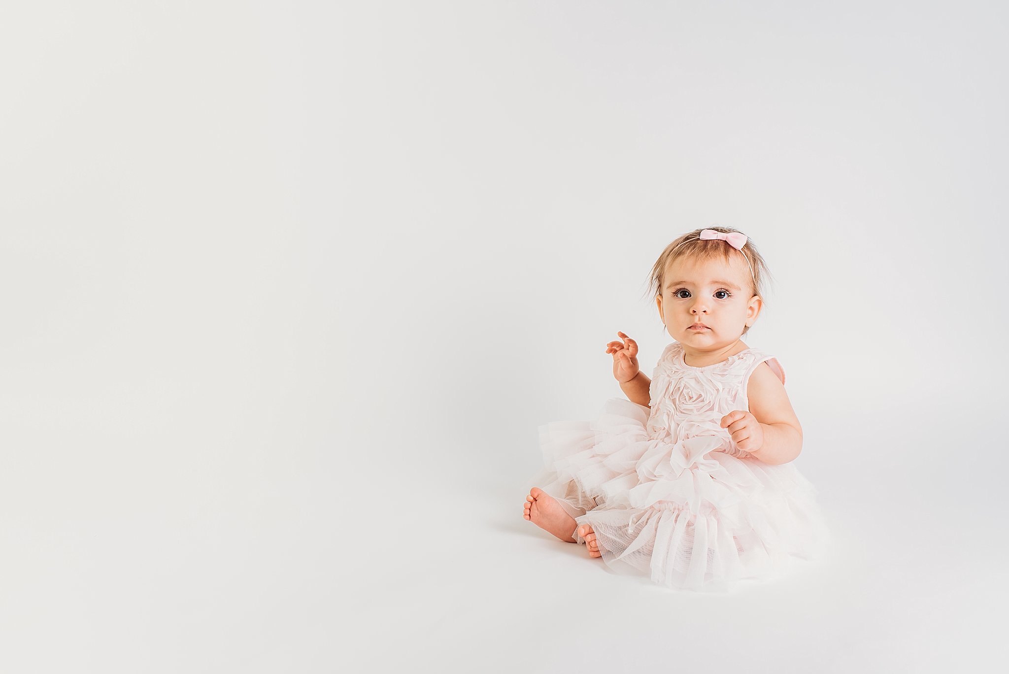Baby sitting on white backdrop in pink dress  | Atlanta Baby Photographer