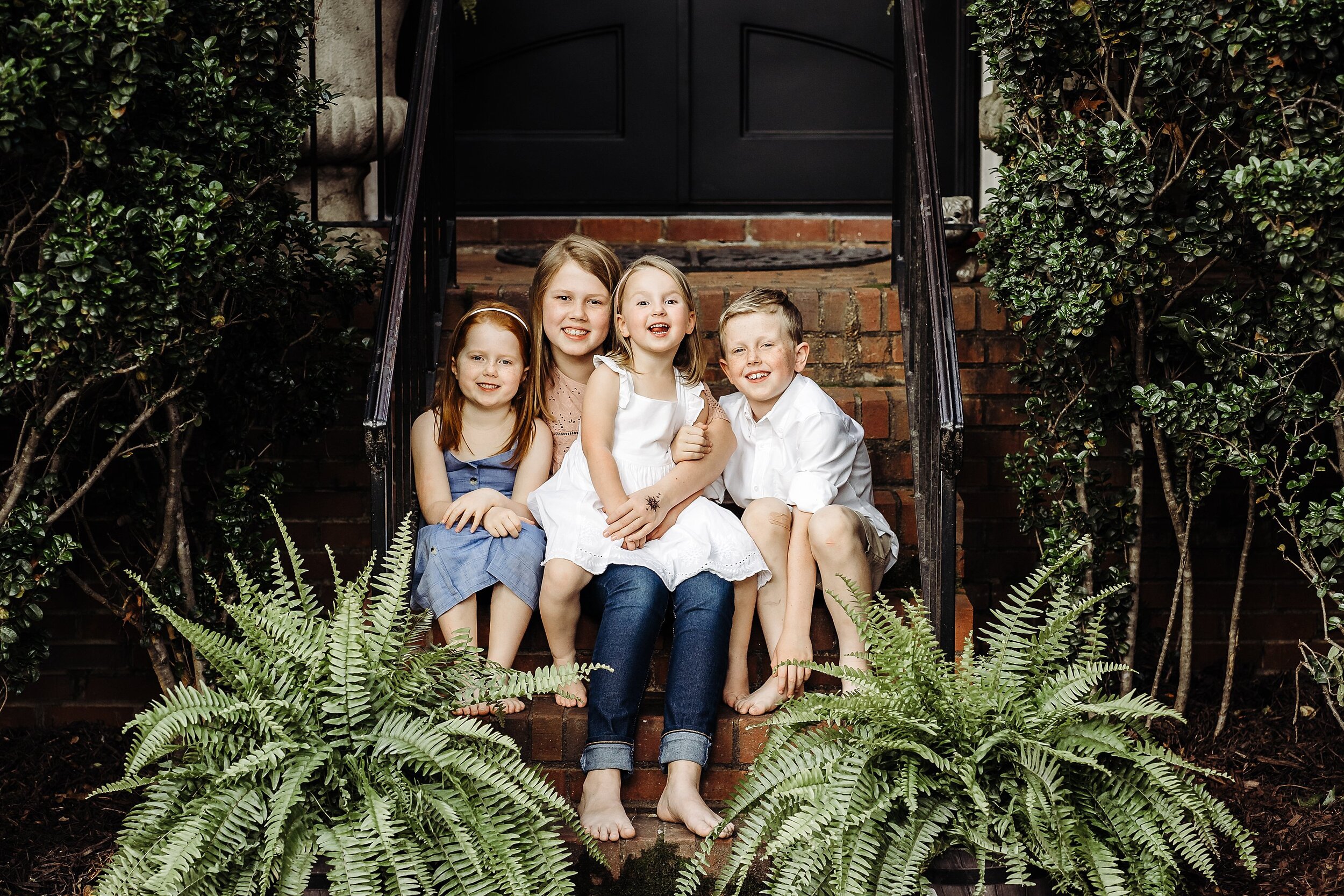 4 kids sitting on brick steps of front porch