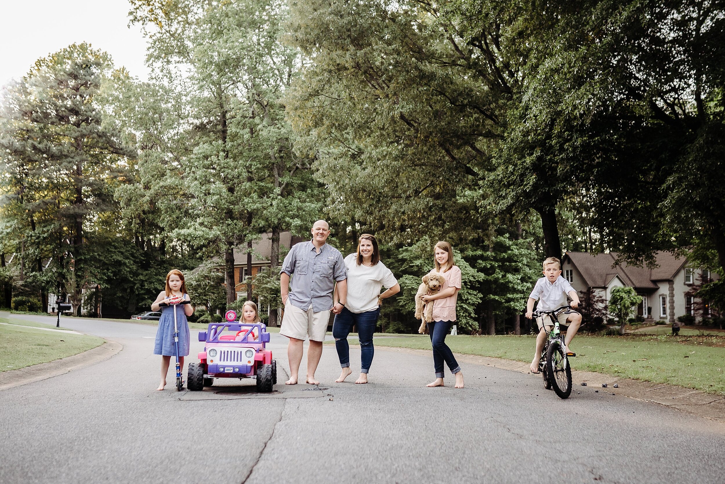 family of 6 on bikes and scooters in neighborhood street