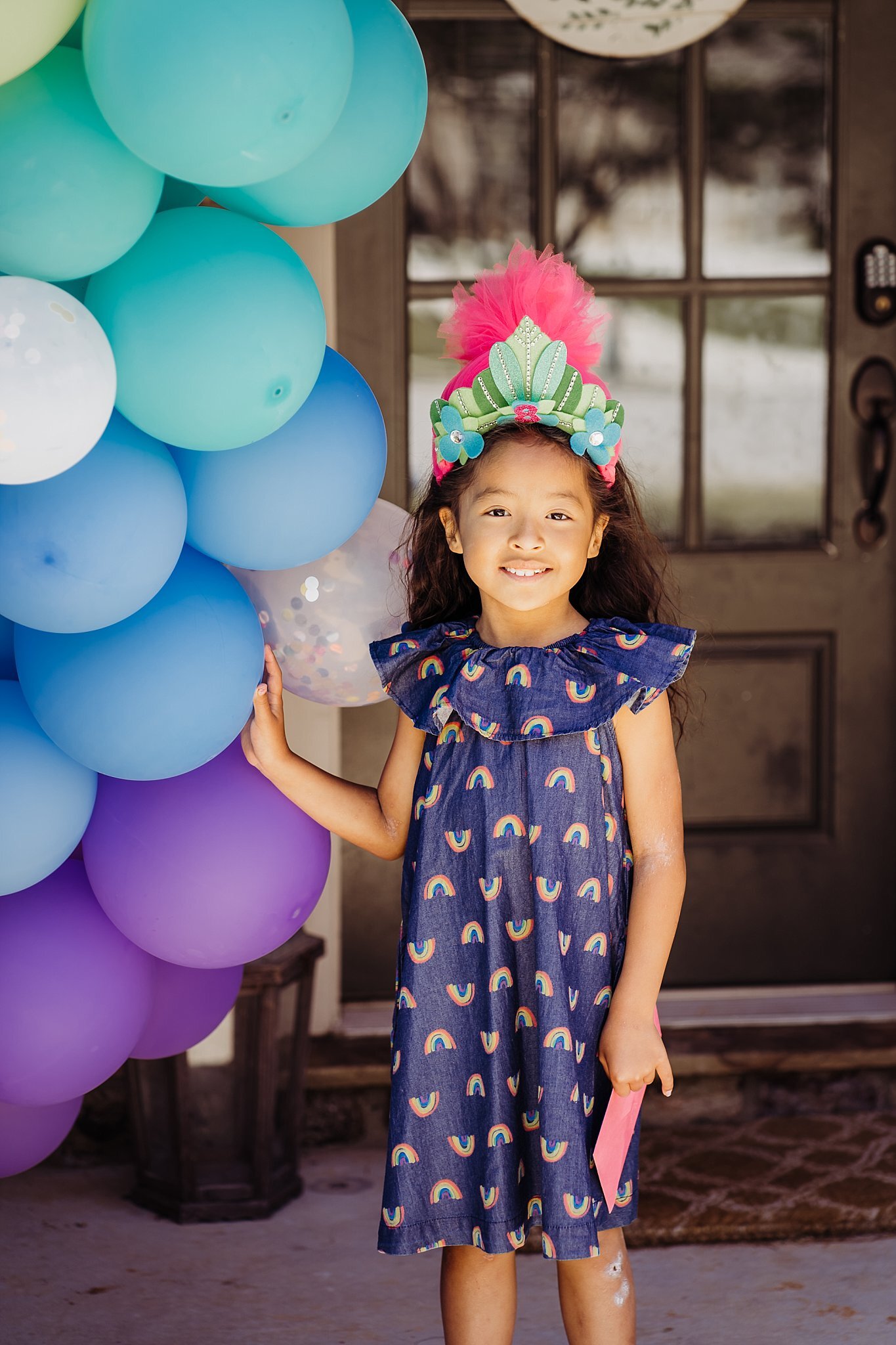 8 year old girl with troll headband next to balloon arch