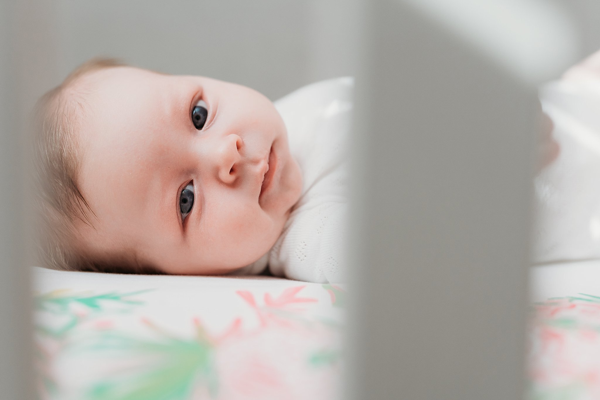 newborn baby girl looking at camera through crib bars | Atlanta In Home Newborn Session