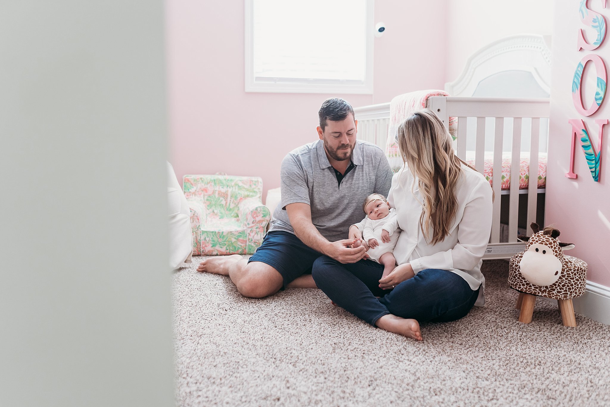 parents sitting with newborn in front of crib in nursery | Atlanta In Home Newborn Session