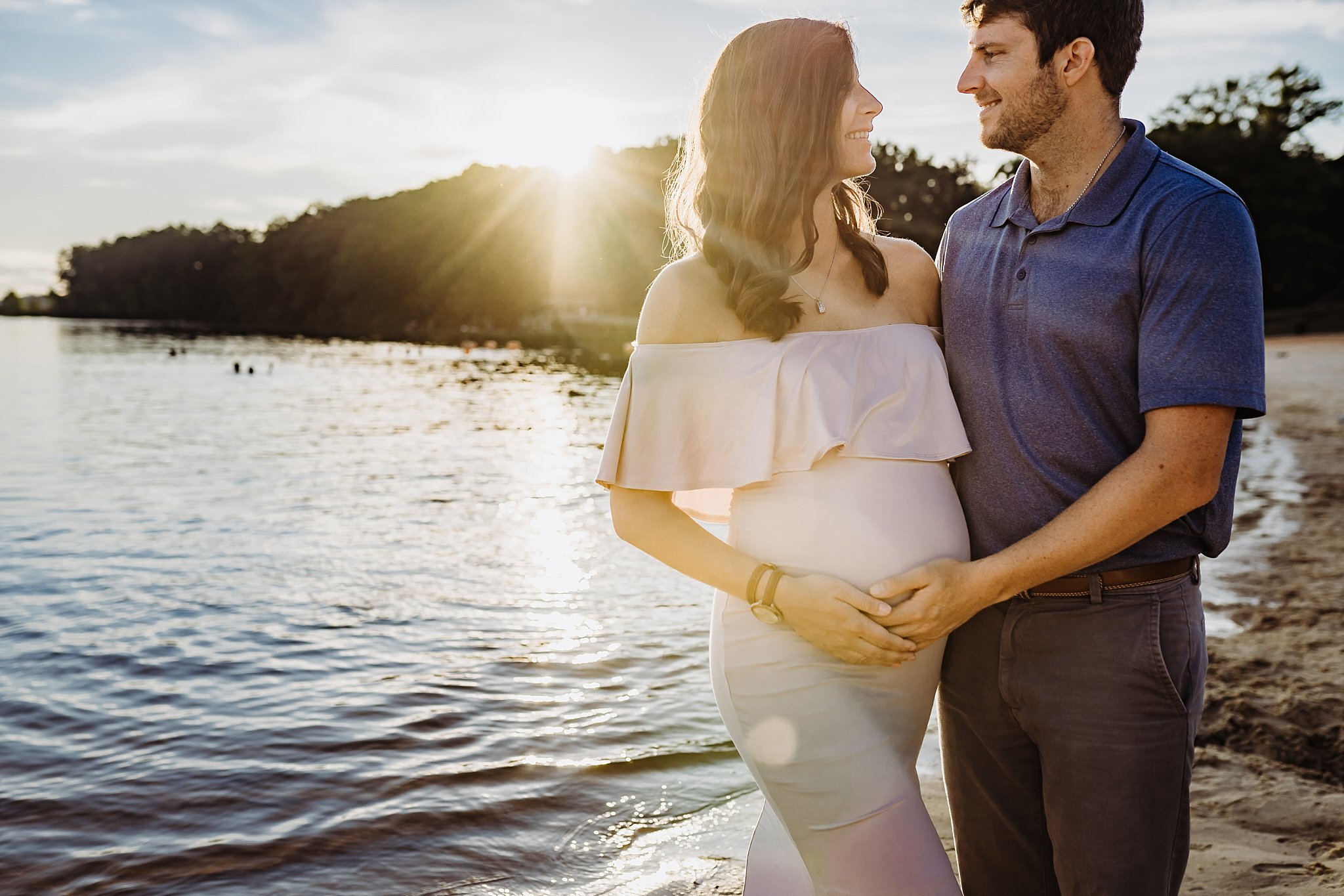 pregnant couple in front of water at Acworth Beach in Cauble Park in Acworth, GA