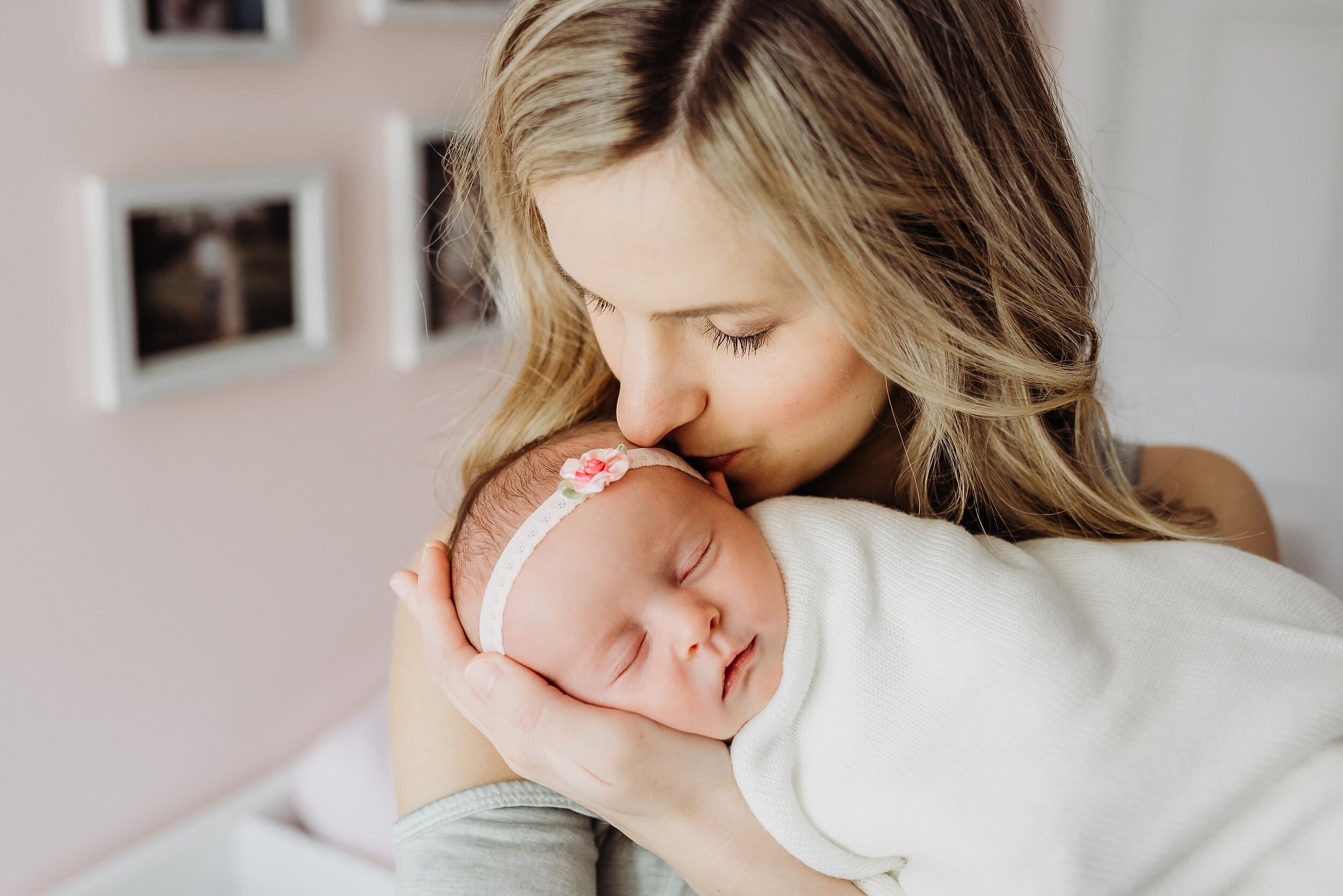 mom kissing swaddled baby's head