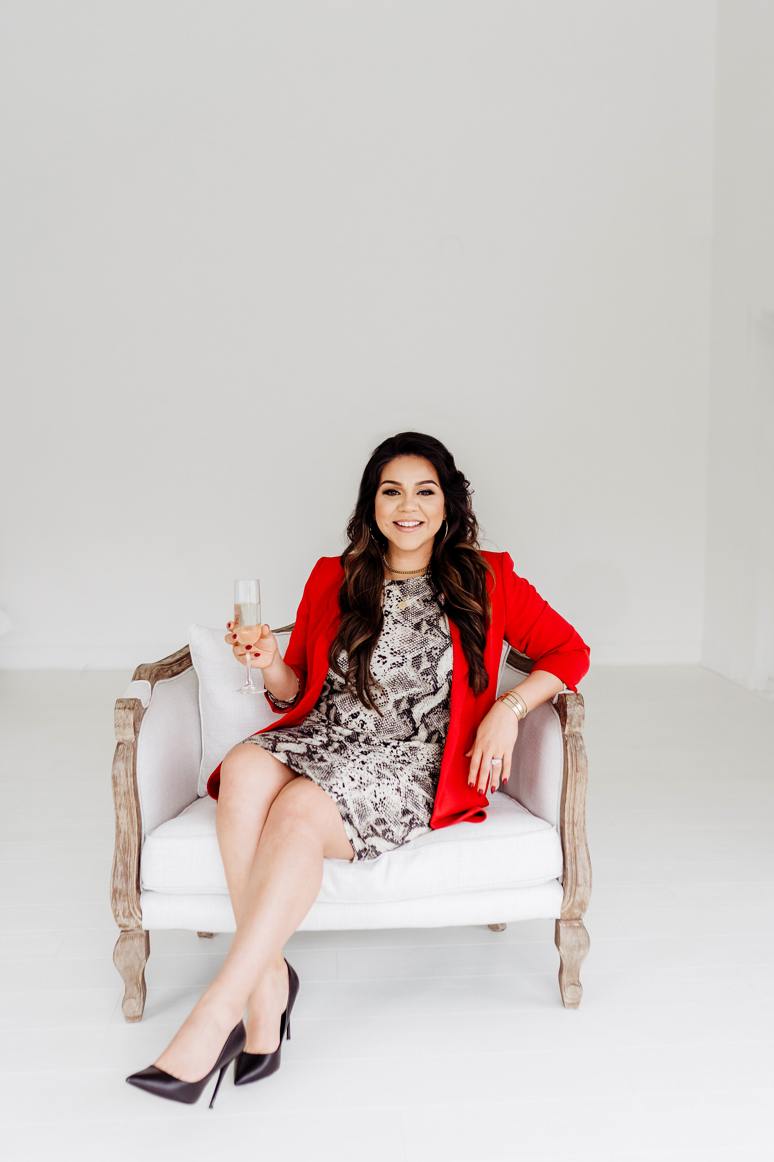 Realtor in snakeskin dress and red jacket sitting on couch Atlanta, GA Personal Brand Photo Session