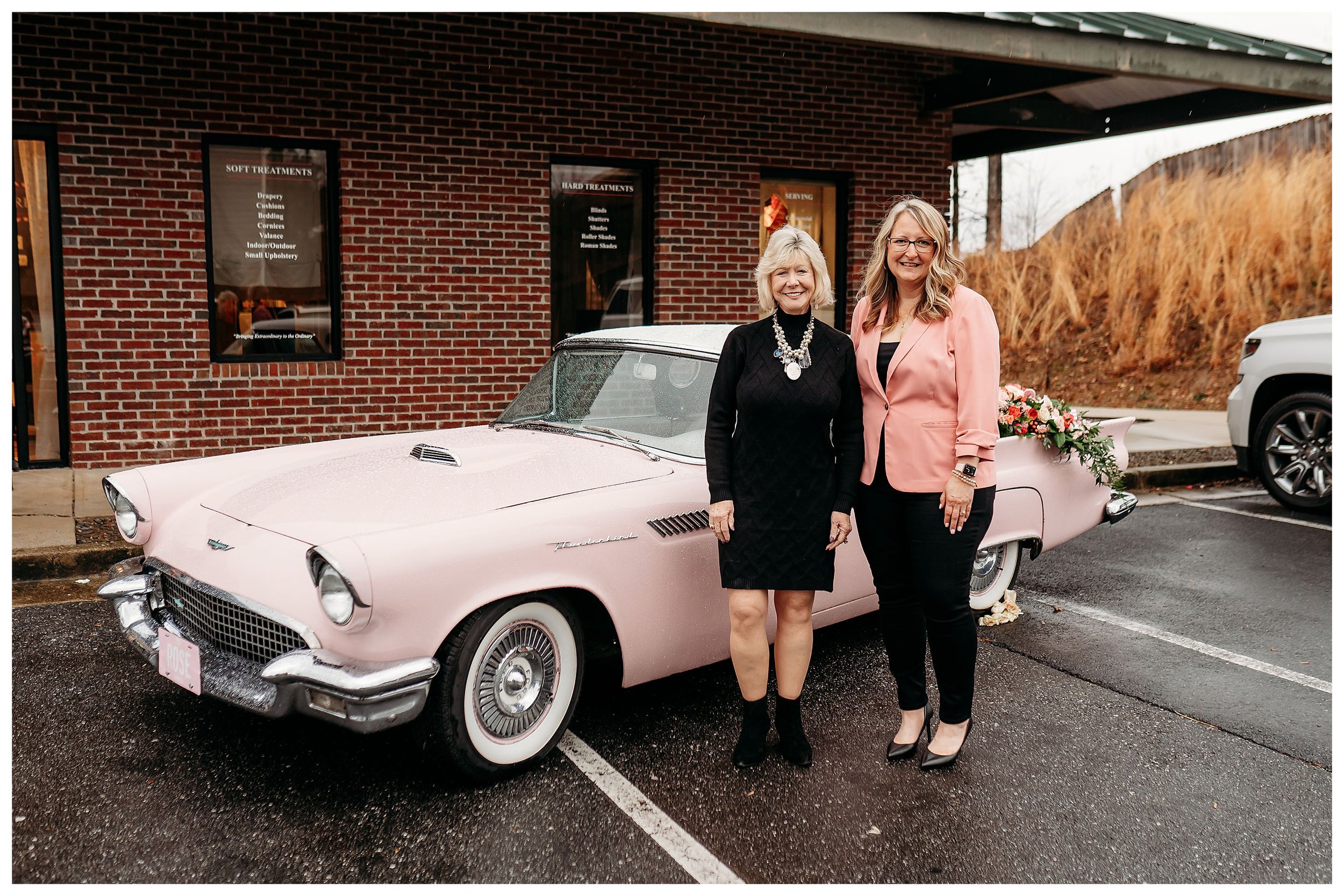 two ladies in front of pink thunderbird at Stitch above the rest ribbon cutting