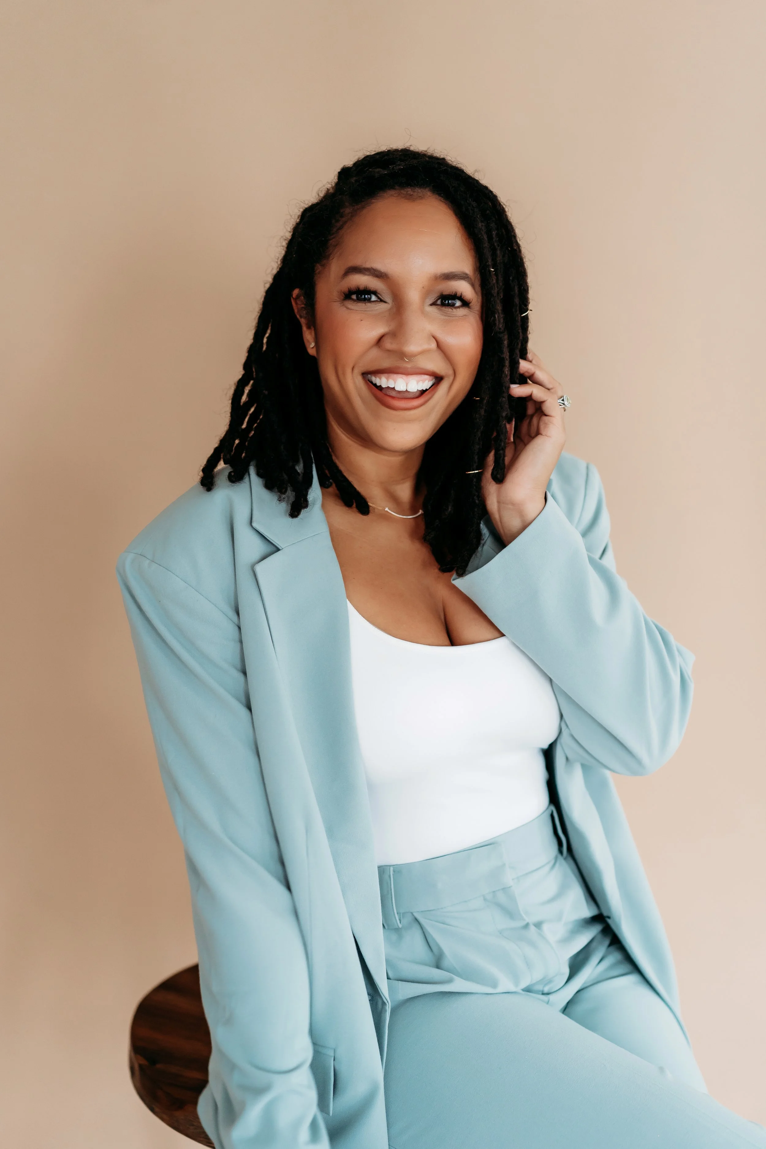 woman in blue suit posing for headshot against tan backdrop
