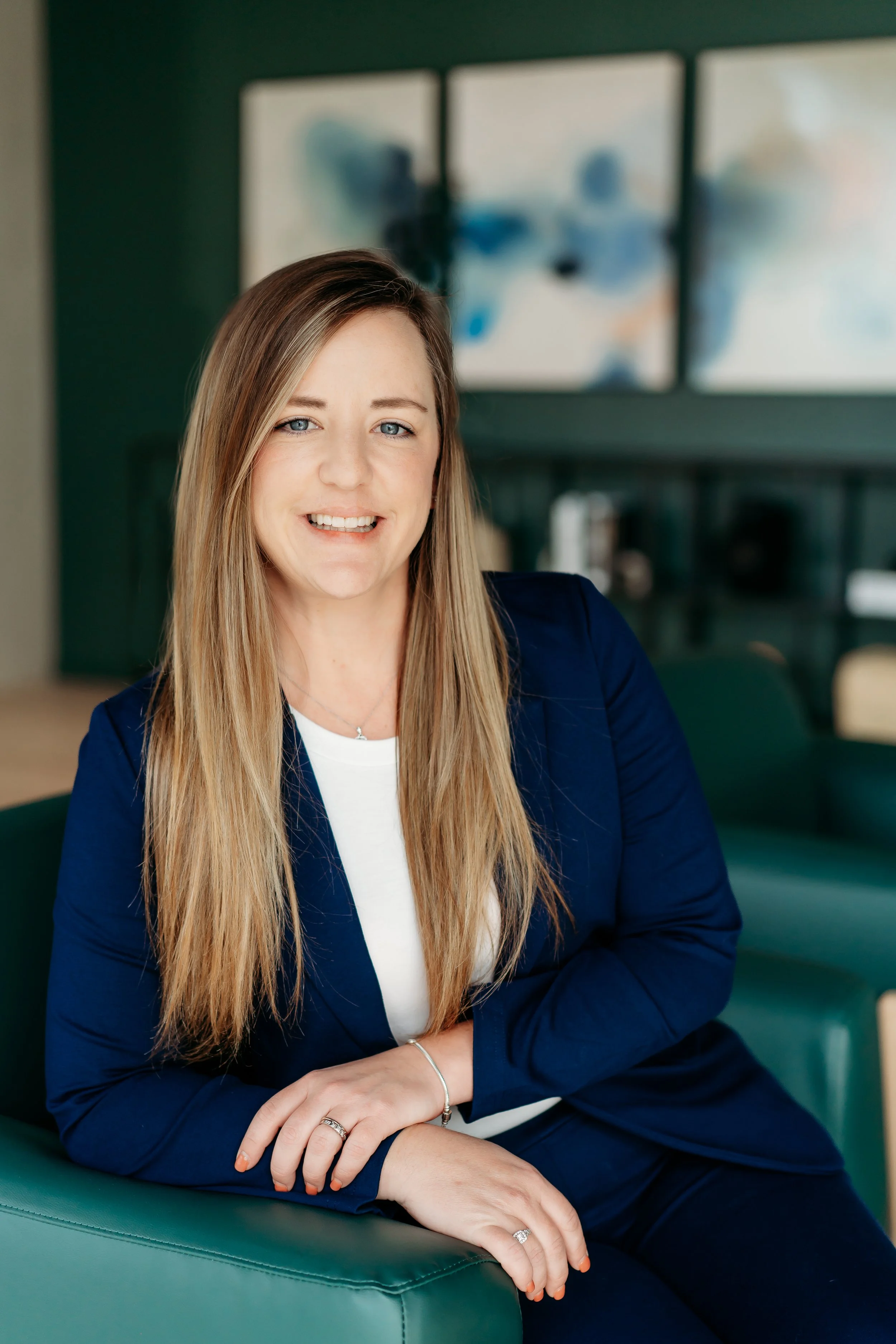 blonde woman in blue suit posing in chair for headshot