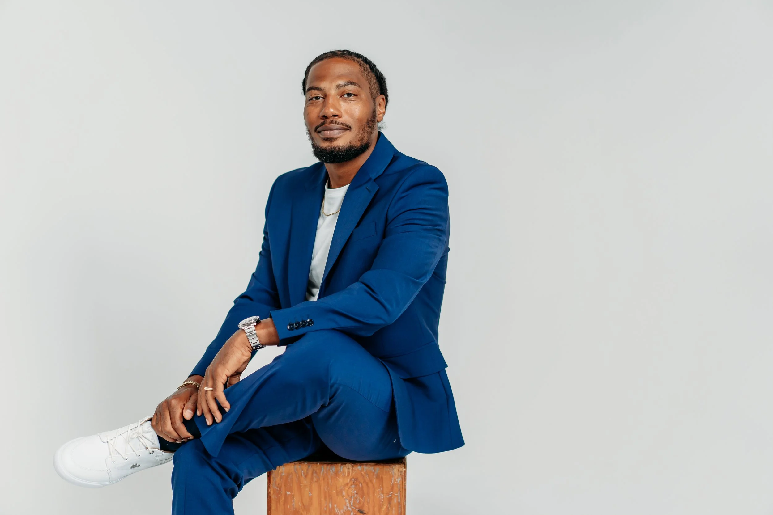Man in blue suit sitting on box looking at camera