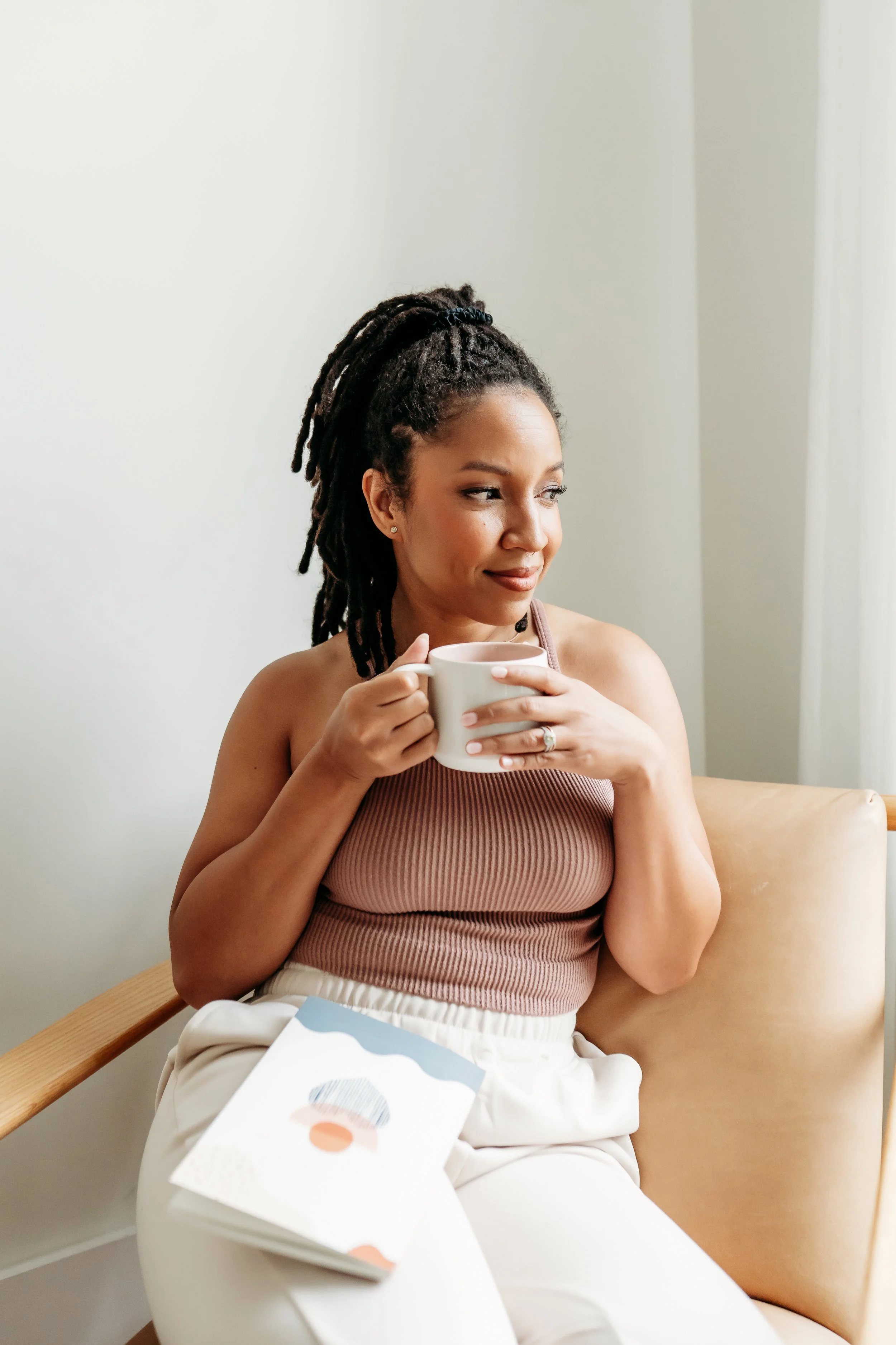 lifestyle brand photo of woman looking out window in studio drinking coffee