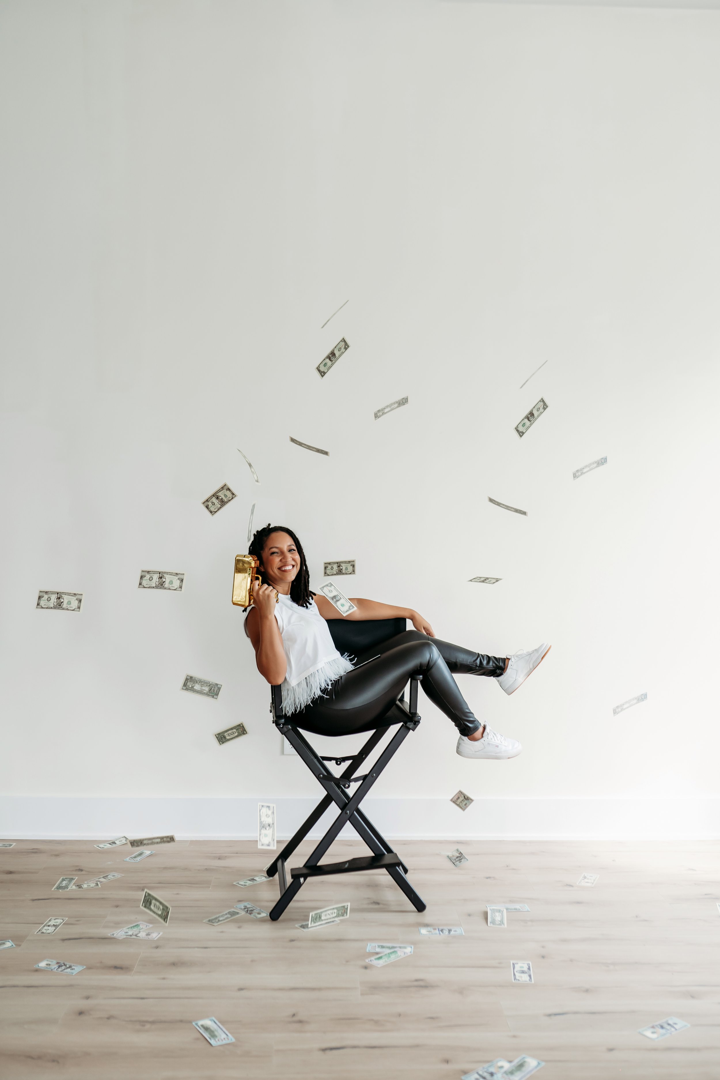 Woman shooting money gun from a directors chair