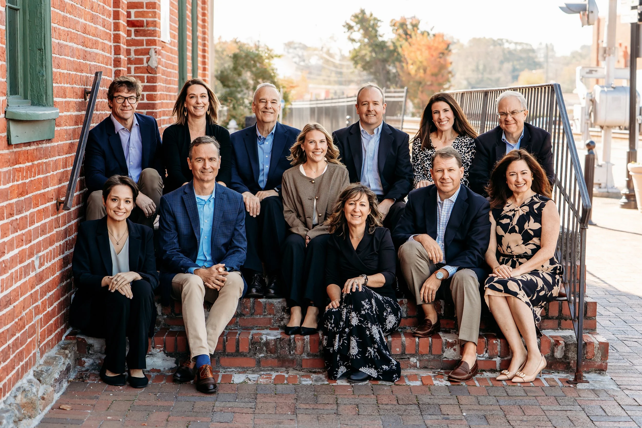 Team of people in suits and business attire sitting on brick steps in marietta square