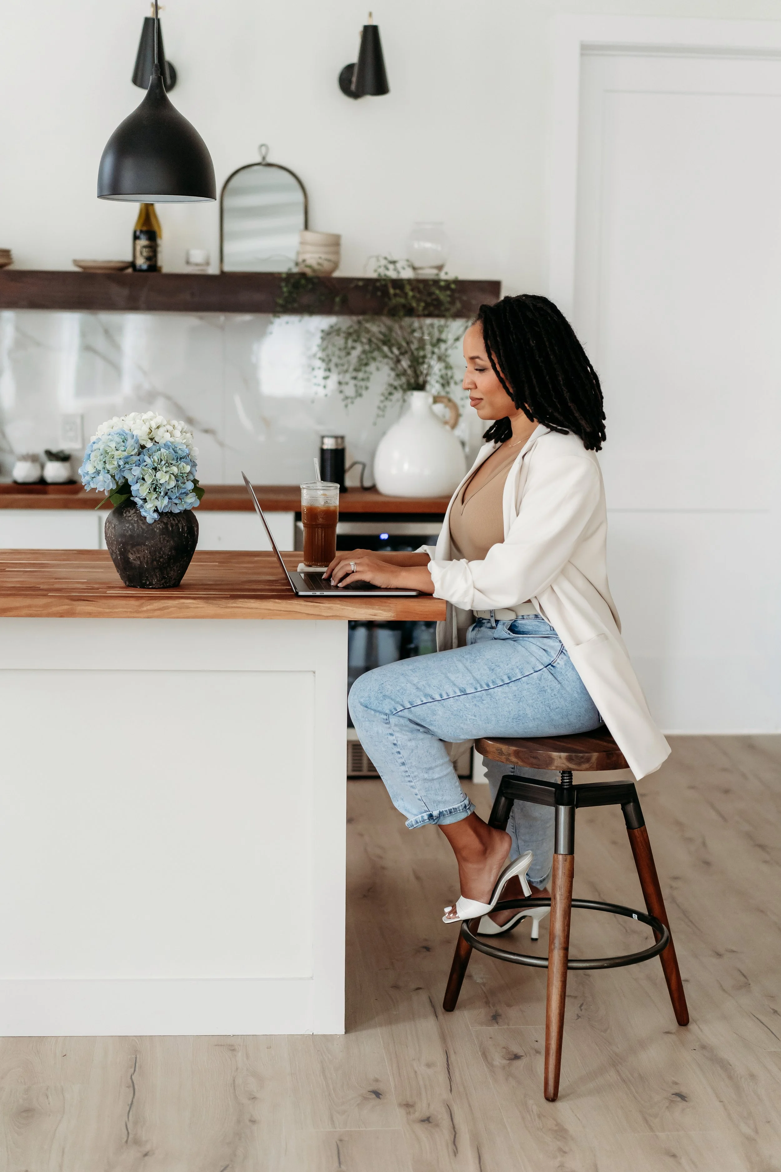 woman sitting at island in kitchen of Alpharetta brand photo studio looking at laptop