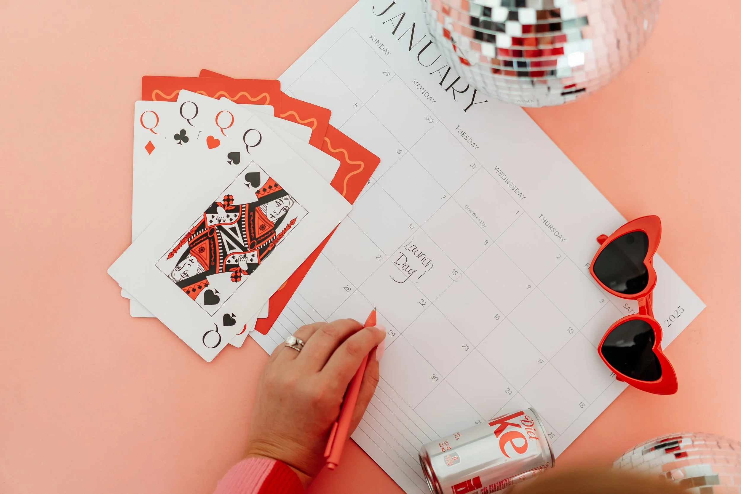 flatlay branding image of calendar oversized cards heart glasses diet coke on pink backdrop 