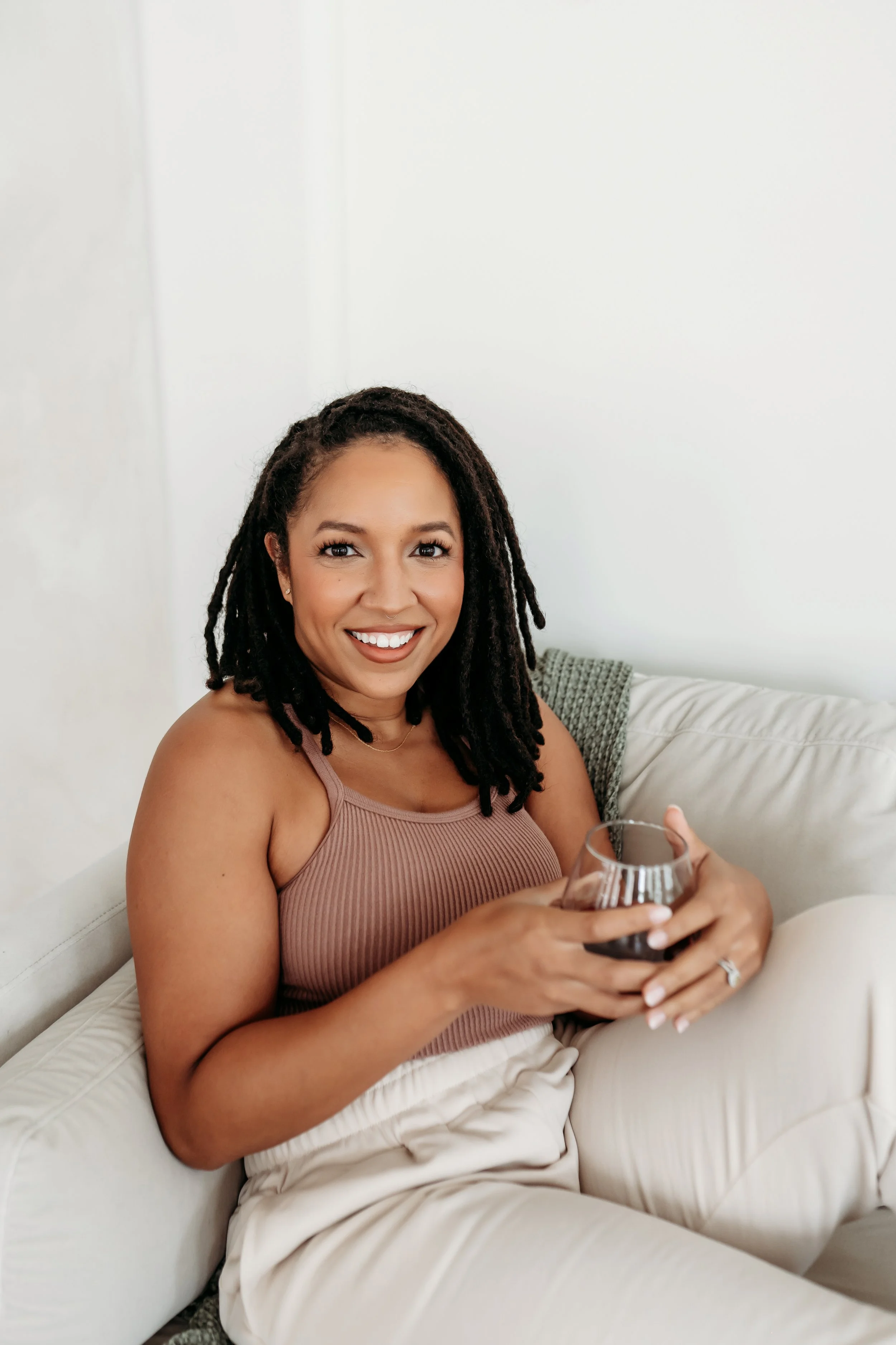 Lifestyle headshot of woman on couch in pink top in Alpharetta photo studio
