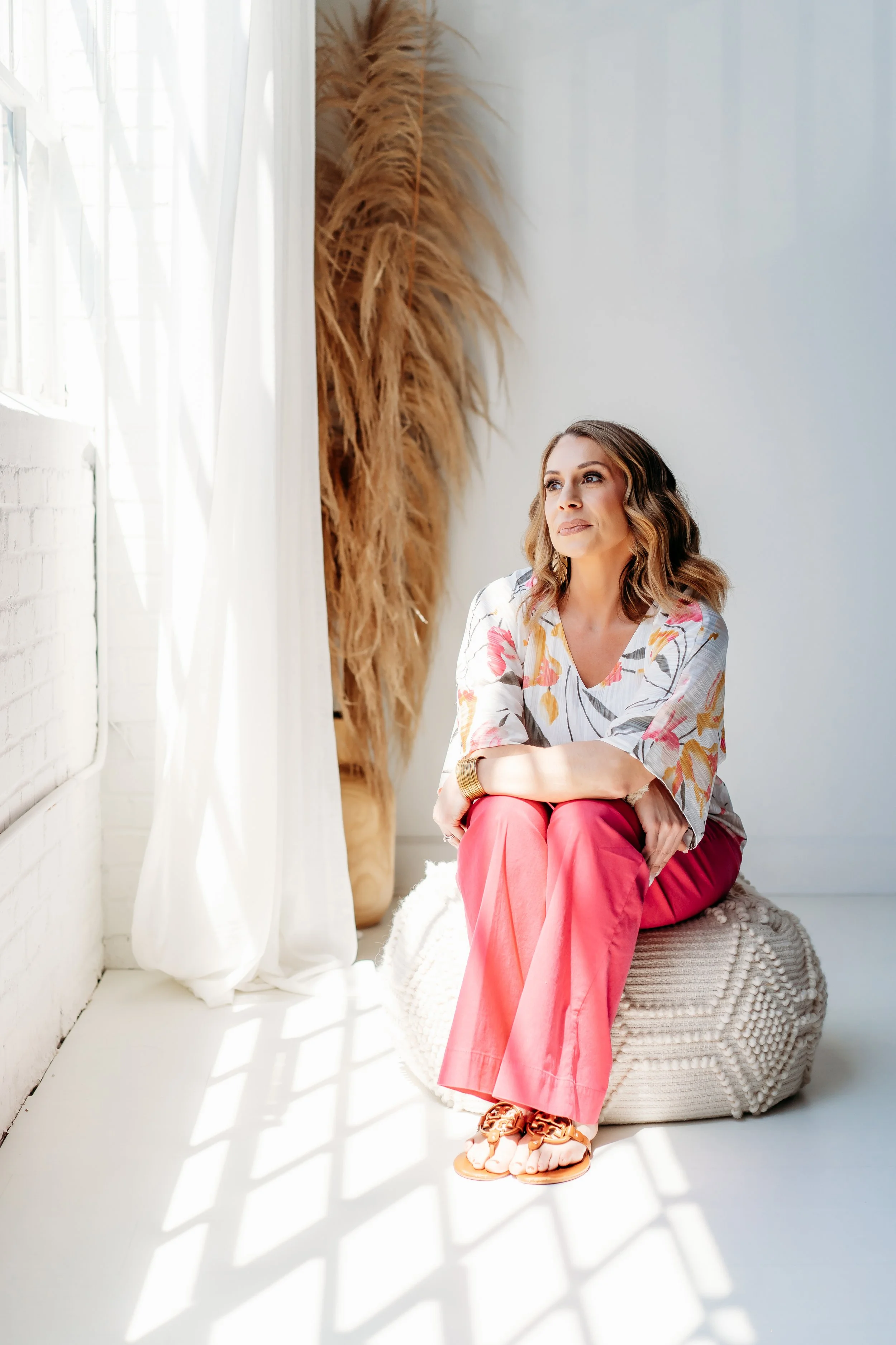 woman in pink pants looking out window of Atlanta Brand Photo Studio