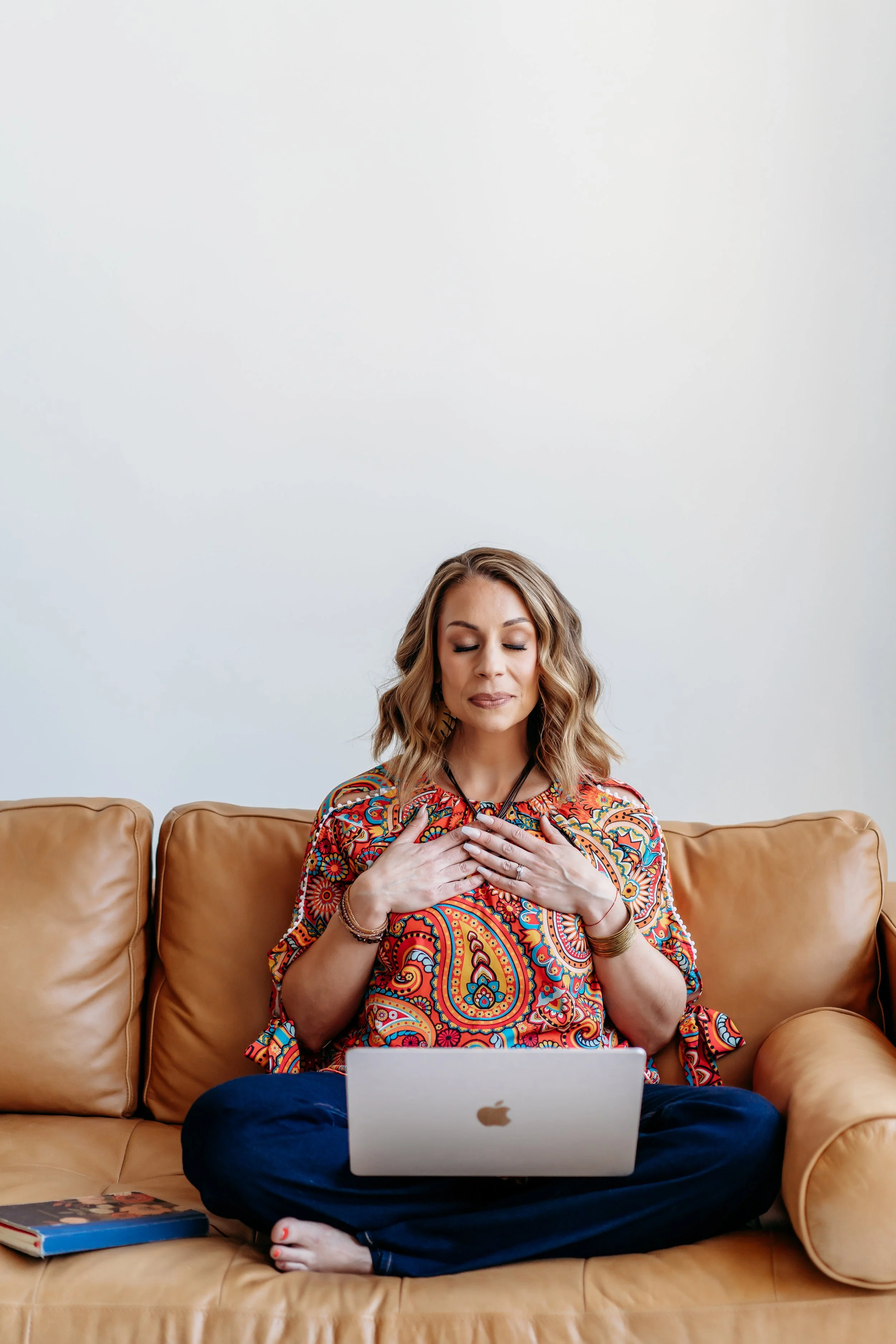 Lifestyle brand photo of Atlanta therapist sitting on leather couch in bright paisley shirt meditating