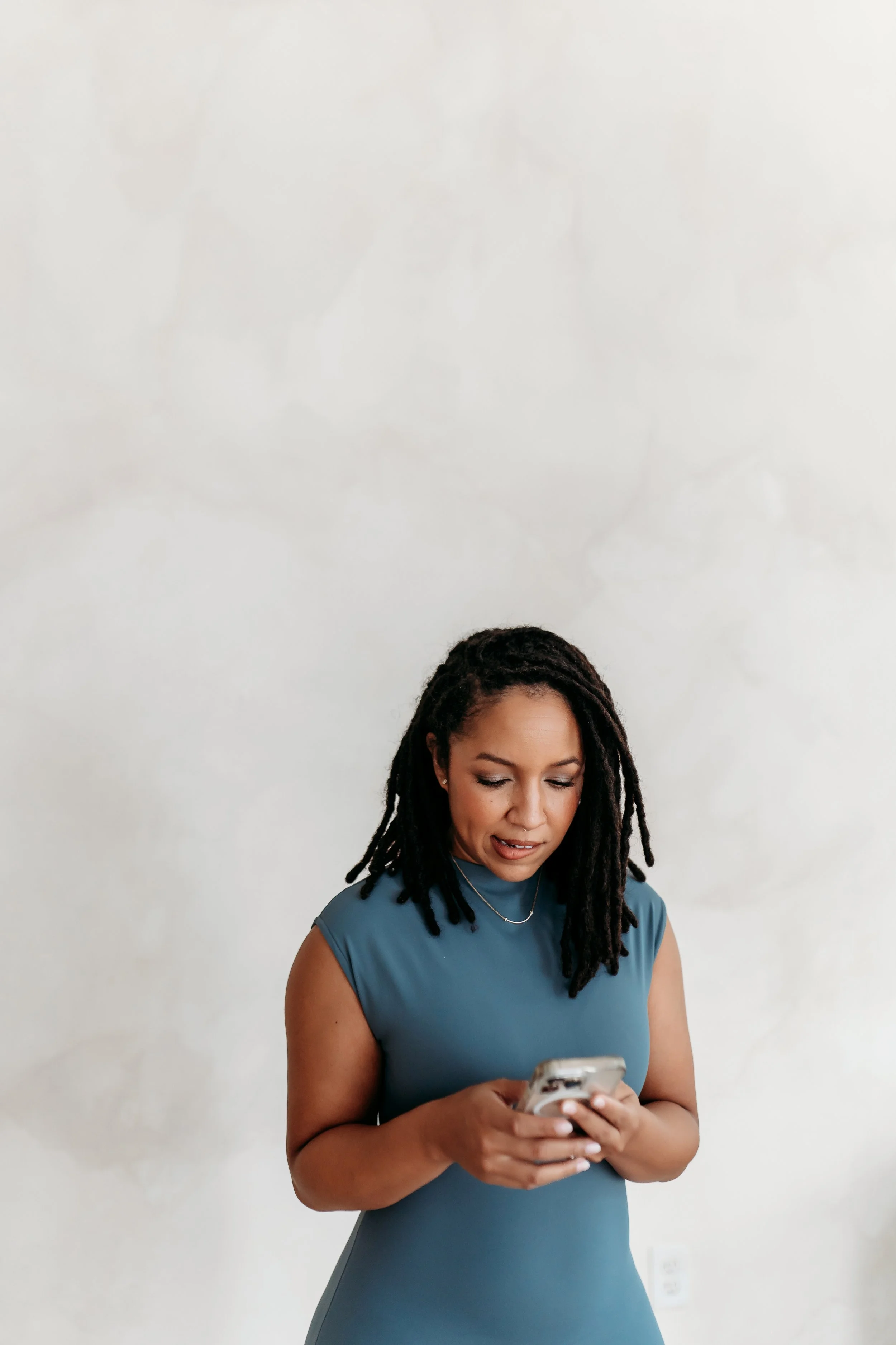 woman in blue dress looking down at phone