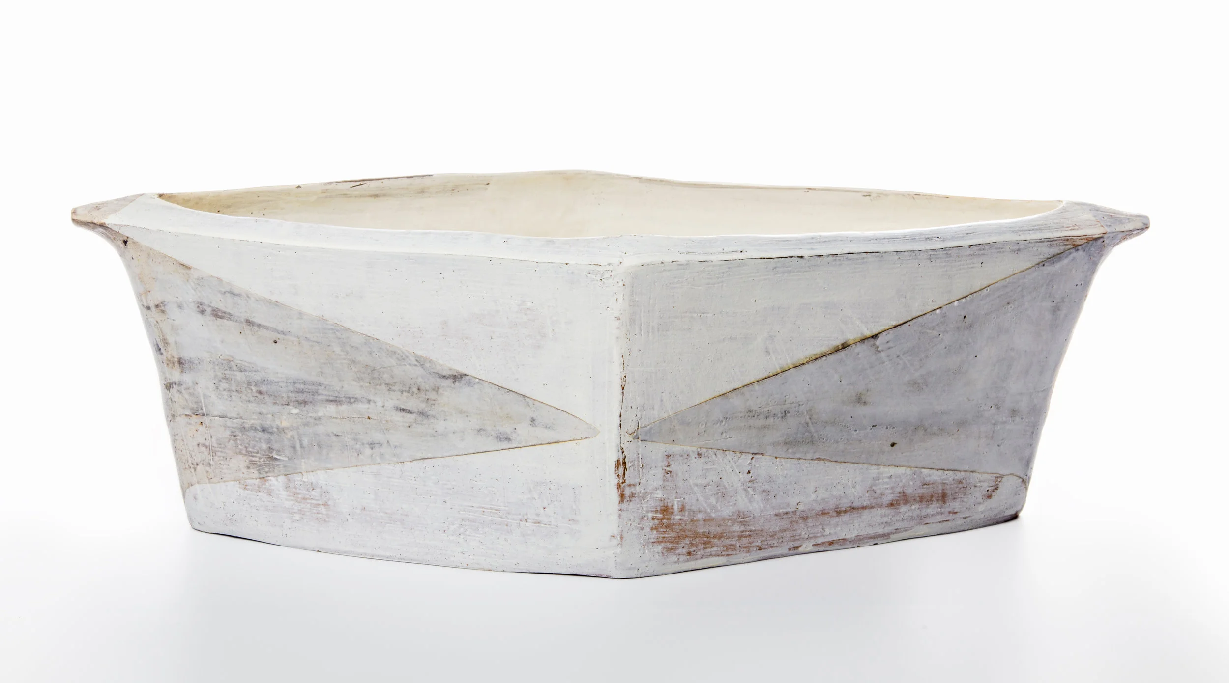 I make hand-built earthenware vessels that draw on the quiet, minimal forms of basic function, such as basins, troughs and baskets. Surfaces emphasize the subtleties of material, process and firing as the primary decorative elements – dragged grog, finger marks, the layering of slips and terra sigillata, and the dulled whites and blacks that come from reduction firing at a low temperature. Smaller pieces like plates, cups, mugs and bowls are wheel-thrown, then scraped and pared down in form and reduction fired. Most recently I have been pulling from my long love of textiles to add pattern and color to this smaller work.