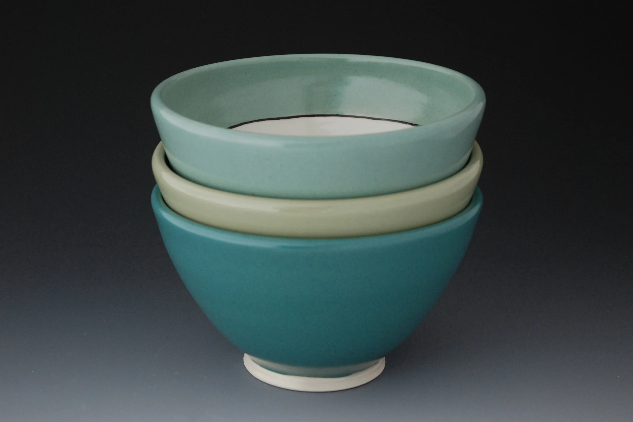 For me, pottery is a blending of both function and aesthetic. While I am very attuned to form, color, and design, drawing much inspiration from nature, I also pay attention to the way my work feels to hold and how easy it is to use. I want the handles of my mugs and pitchers to have a comfortable grip, for example, and I curve up the edges of my plates slightly so sauces don't run off and peas don't escape. My pots each display evidence of the process I use to create them. In our society dominated by mass production and faceless corporations, handmade objects introduce human connections that I think we all yearn for. I want to draw the user in to look at the differences in subtle details of my work: the way the lines travel around the pot, the point at which they waver or are sharp and crisp or how the glaze breaks over a curve. I hope that the daily use of my ceramics will remind the user of the slower, handmade, and local aspect that they can choose for their lives.