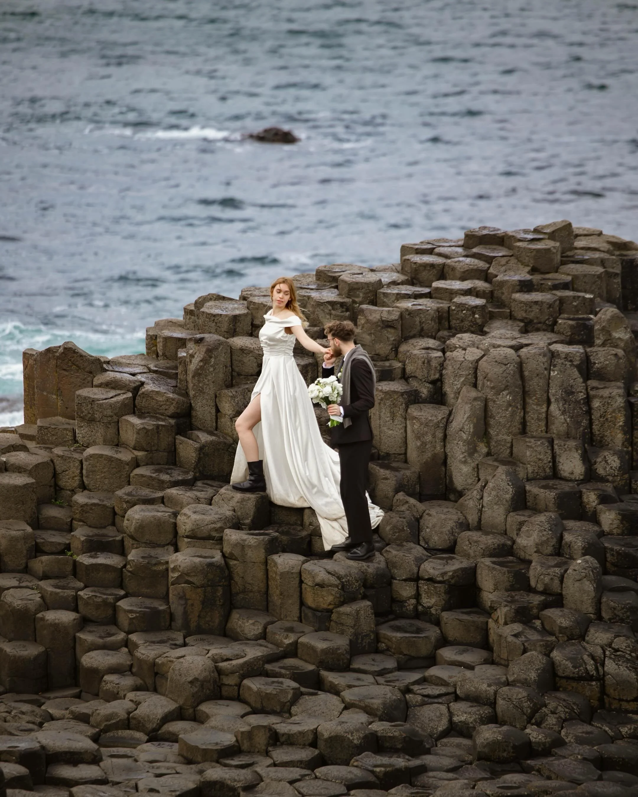 A love story written in stone and sea.
&bull;
&bull;
Host: @vowandventure.co 
Model: @london.model.couple 
Dress: @thewildveil 
Florals: @yescasflowers 
&bull;
#GiantsCauseway #IrelandElopement #DestinationWeddingPhotographer #IrelandWeddingPhotograp