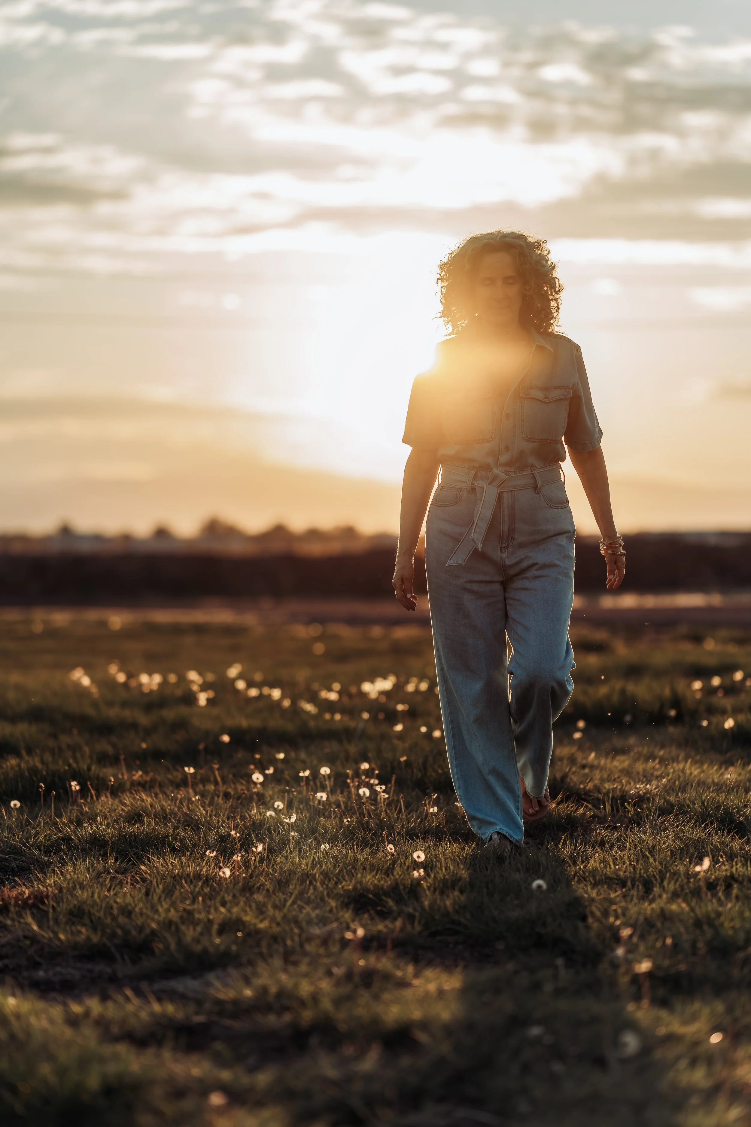 janine in denim pantsuit walking in field at sunset