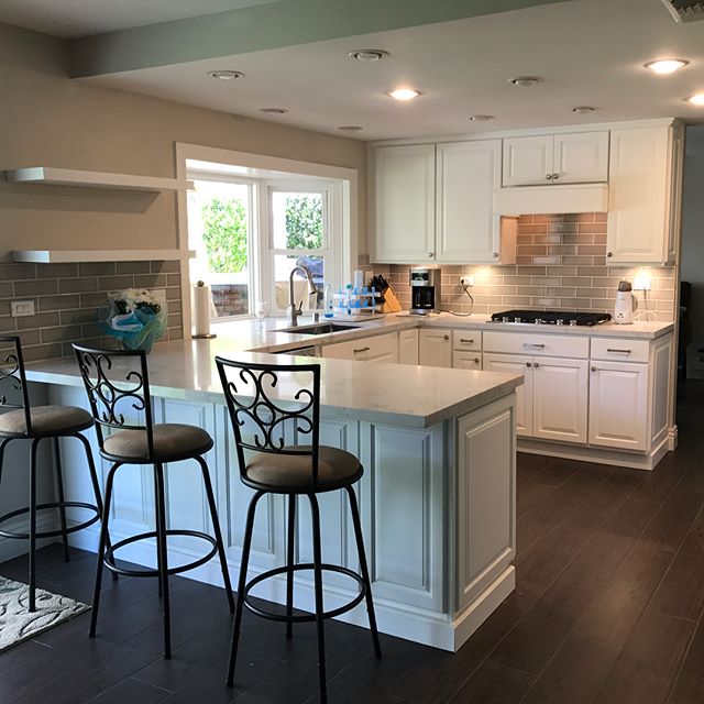 Kitchen and TV console refinished along with some custom woodwork. Decor panels were added giving the island presence and a more finished look. Grey subway tile were also installed along with new electrical. Lastly wood floor  was also replaced with 