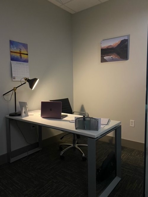 Picture of a private office with white and gray modern desk, office chair and desk lamp.