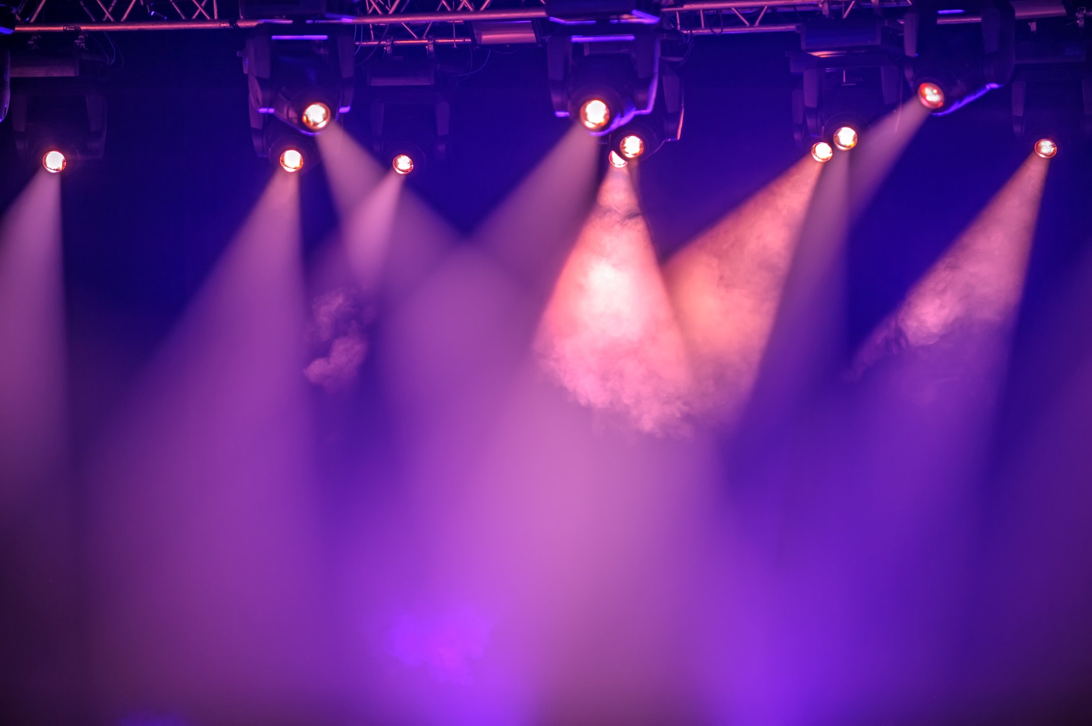 Stage with purple and pink lights shining down, creating a vibrant concert or event atmosphere.