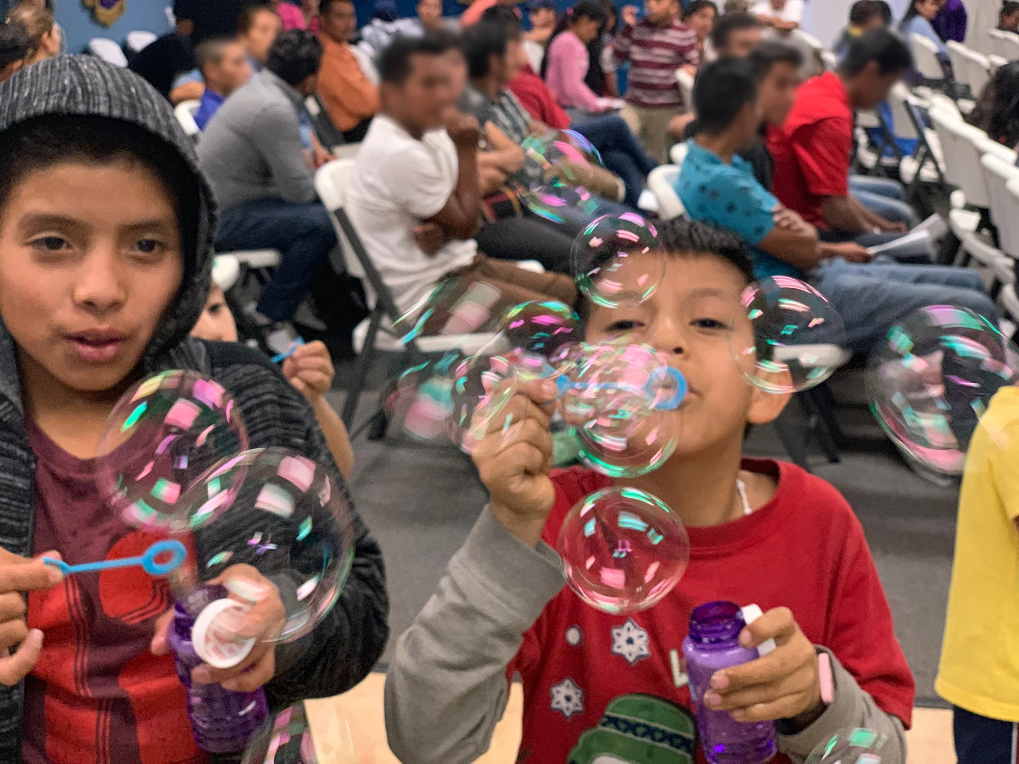 Without complaint, asylum seekers sat quietly in rows of chairs in the church sanctuary waiting for instructions and assistance, and patiently enduring—sometimes enjoying—the bubble-blowing exuberance of the children.